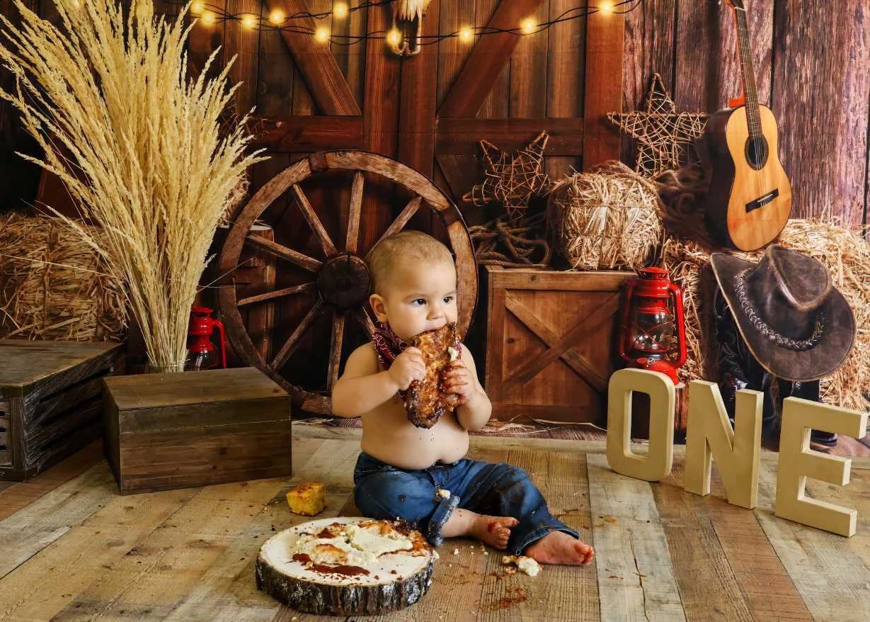 Rustic barn setting with wooden decor, wheat bundles, and candles arranged for a photo session.