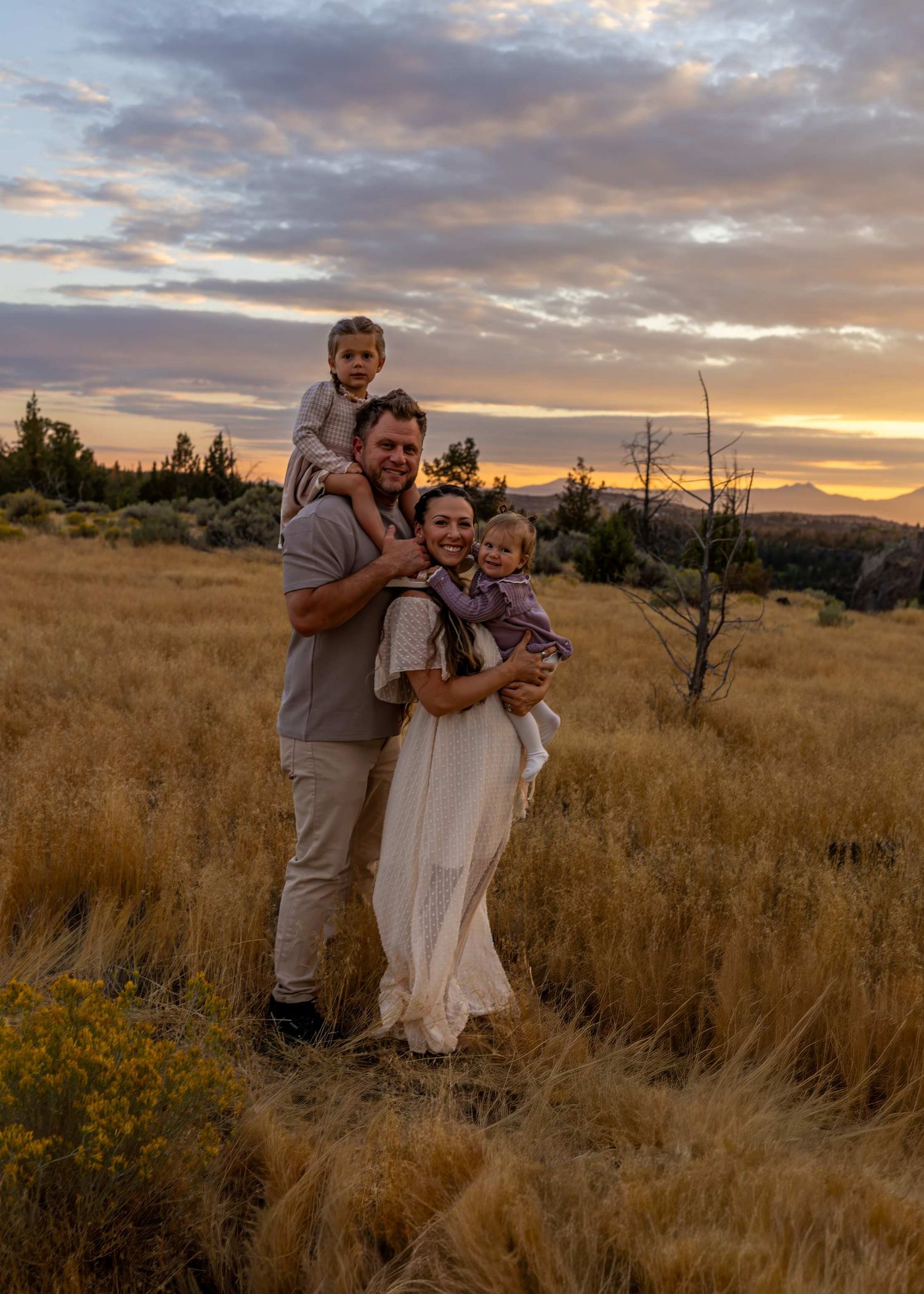 Family shares tender moments in golden field during sunset.