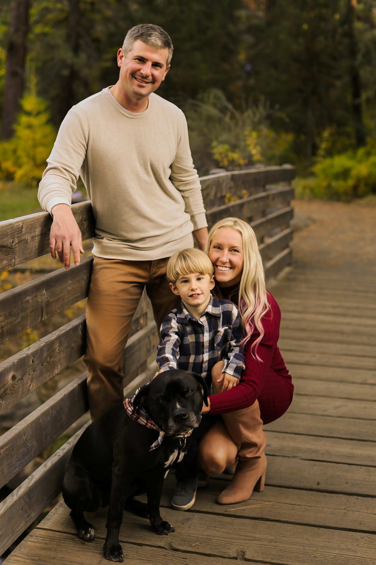 Family shares joyful moments together on a wooden bridge surrounded by autumn foliage.