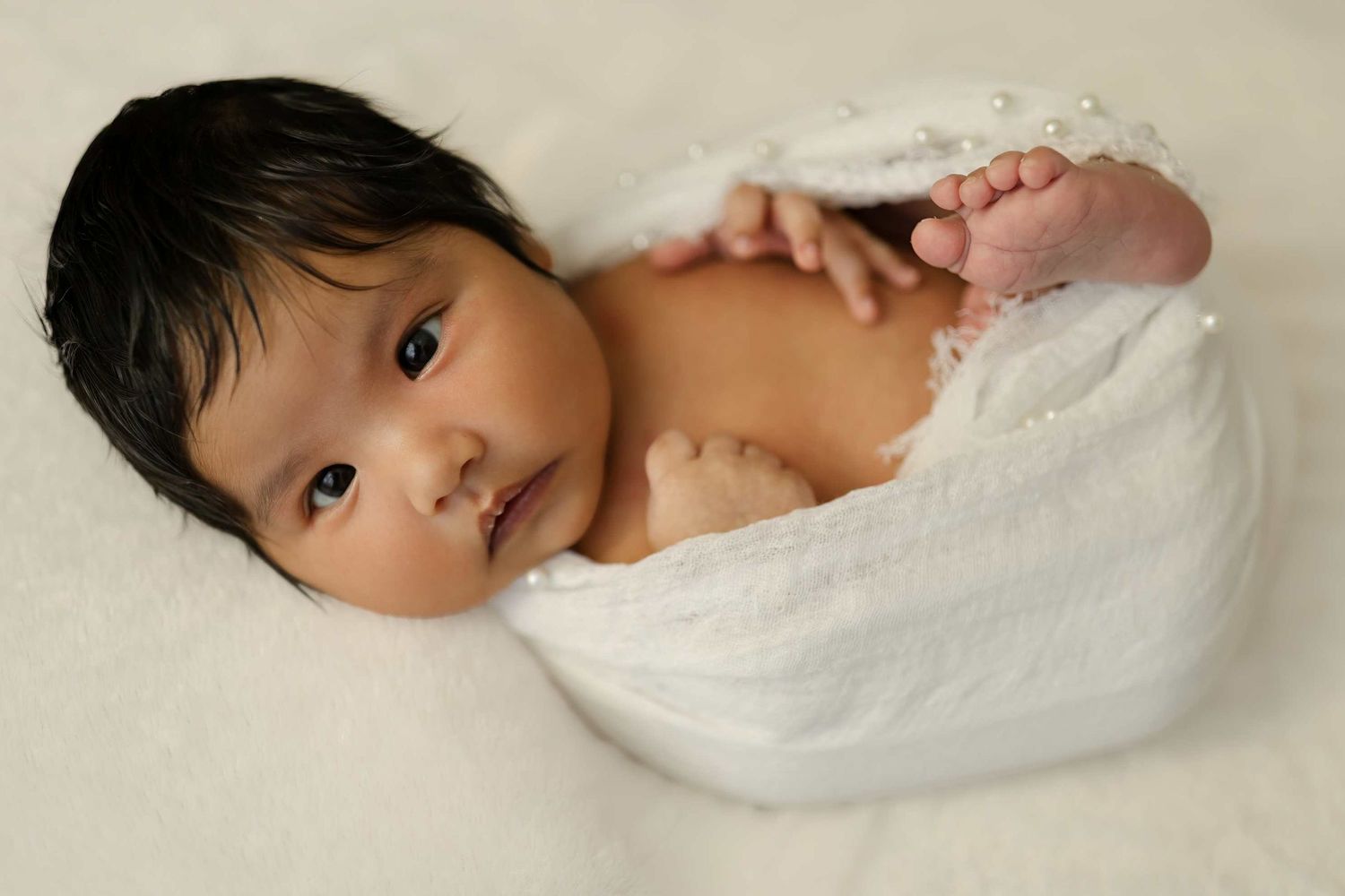 A series of four connected photos showing a baby lying down on white blankets in different sleeping positions.