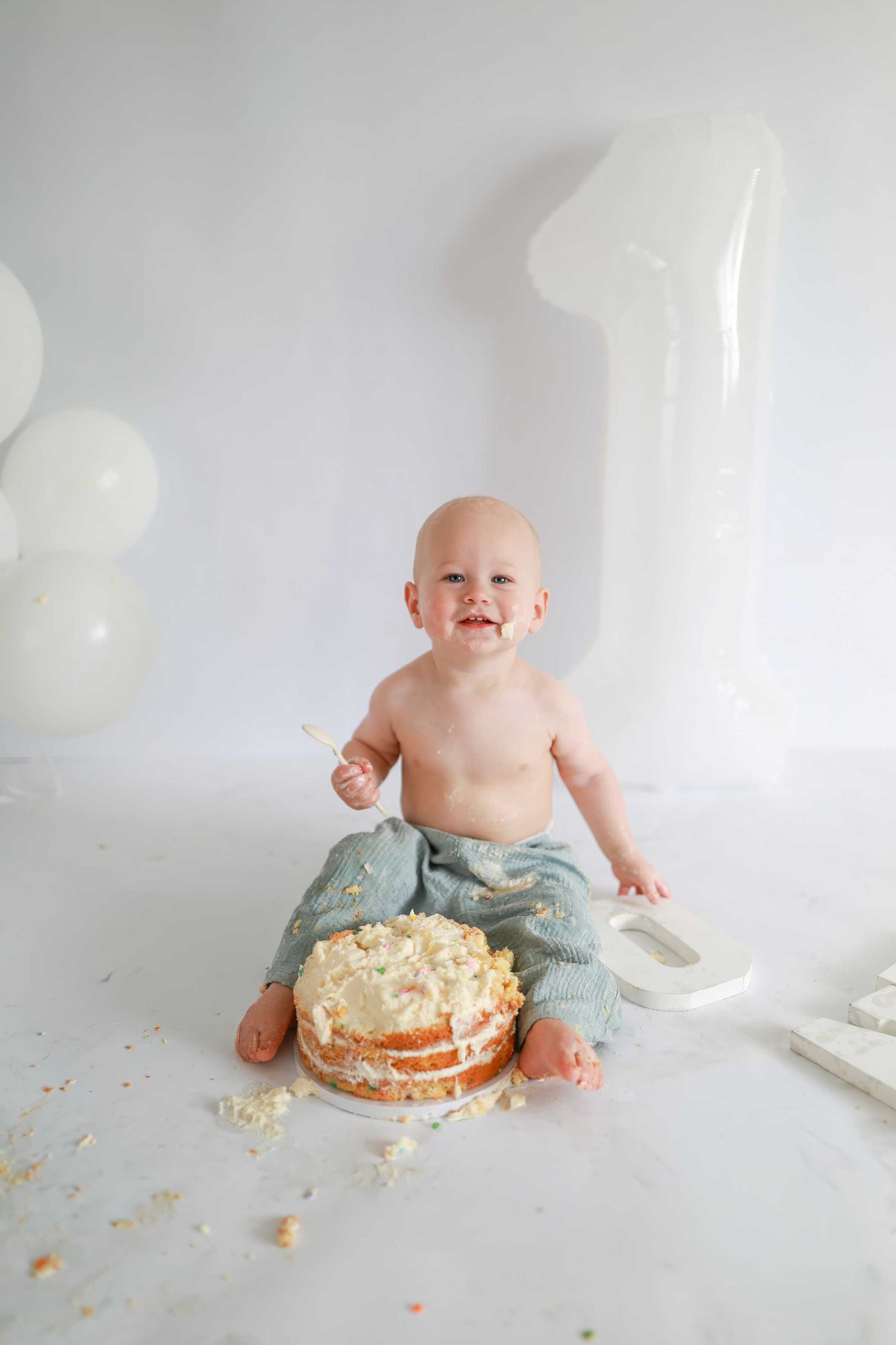 Baby's first birthday cake smash with white balloons and number one decoration on white background.