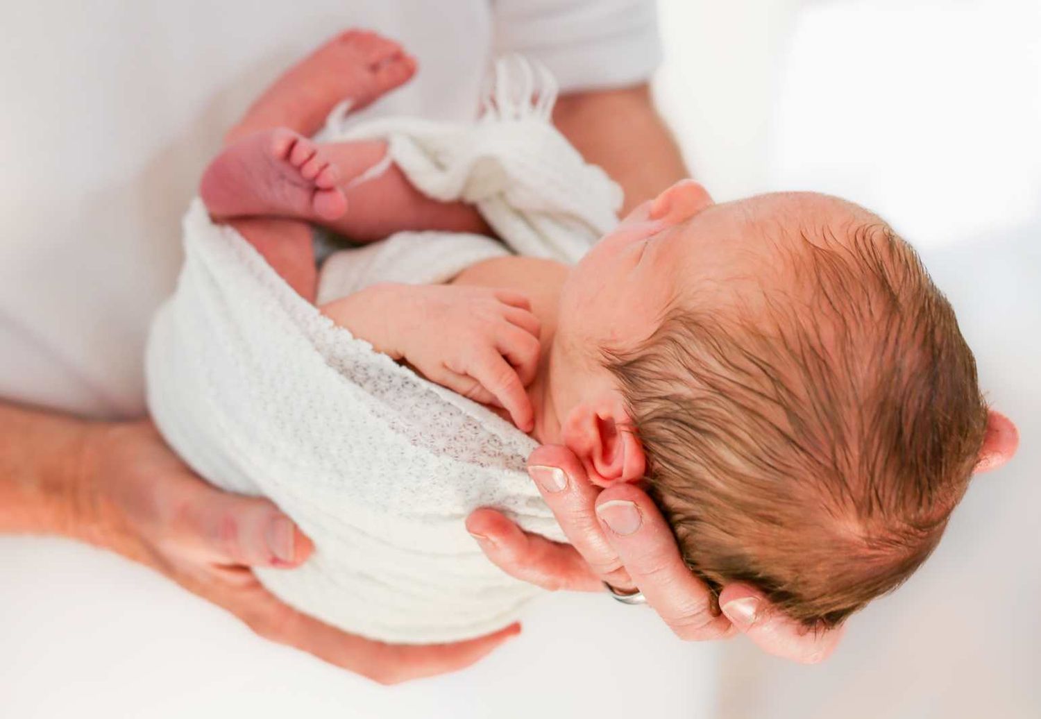 Peaceful sleeping baby swaddled in white blanket viewed from different angles.