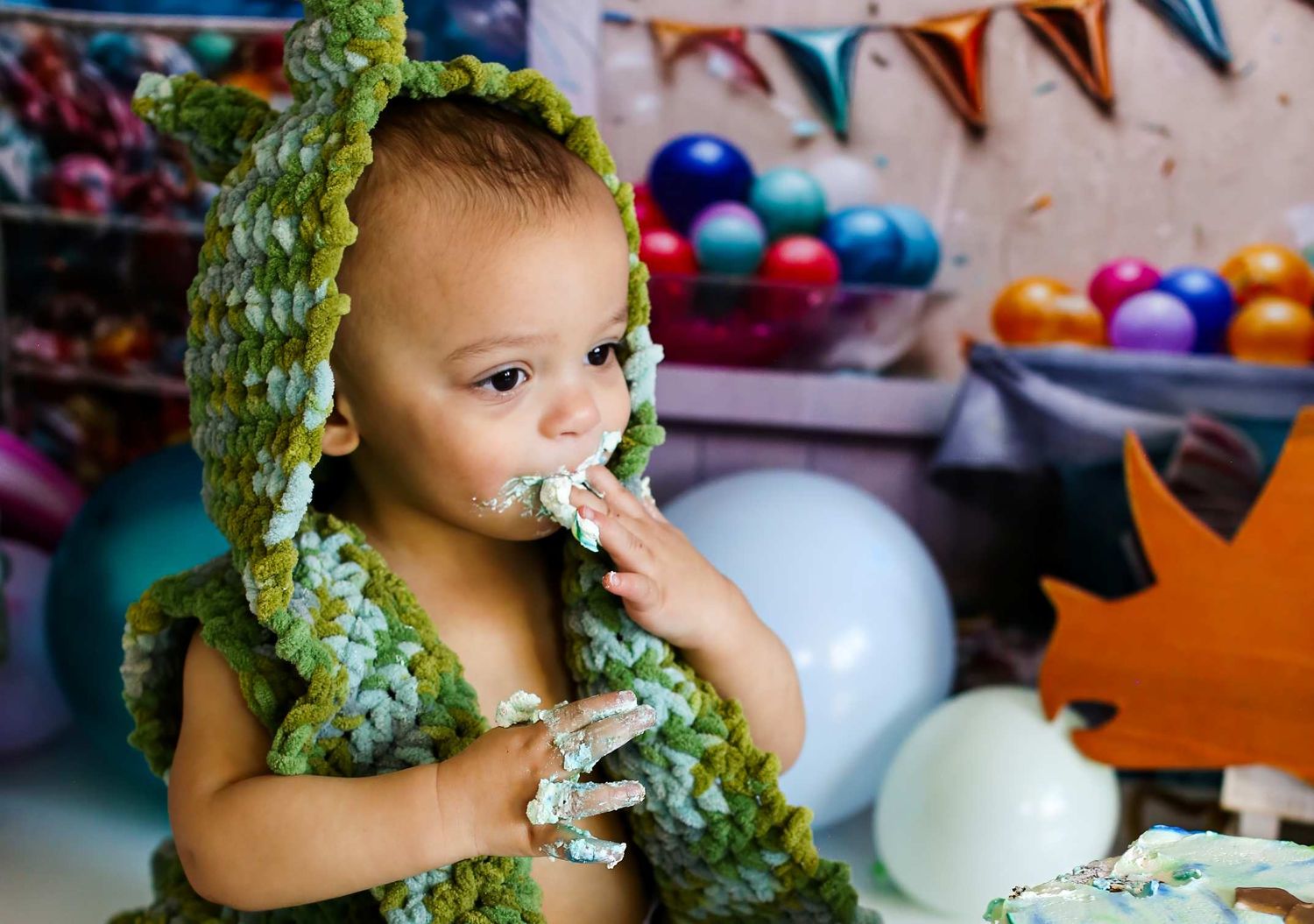 Close-up shots of baby wearing green leaf garland during cake smash session.