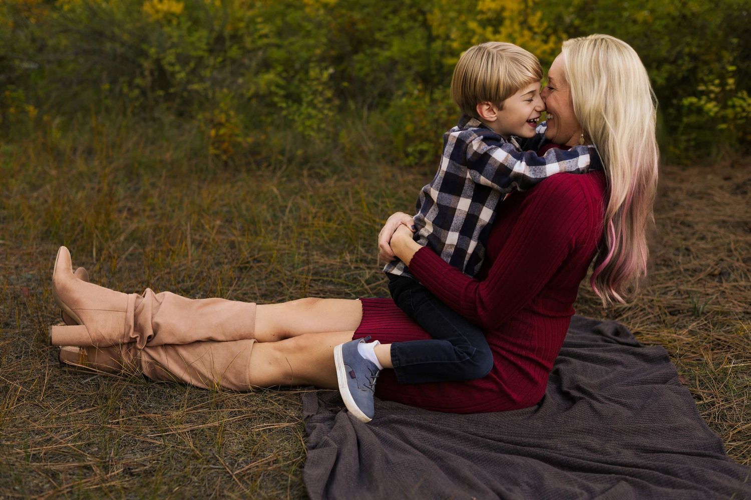 A couple embraces on fallen autumn leaves in a forest setting during a romantic photoshoot.