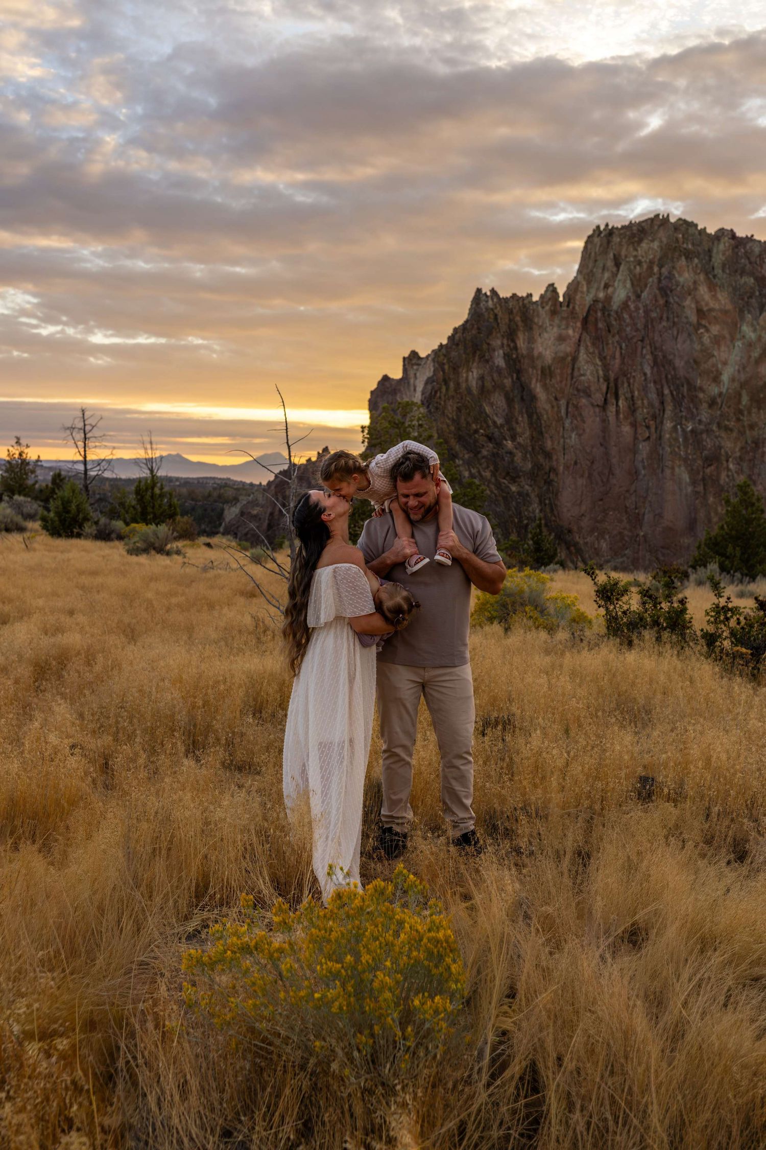A romantic photo session near rocky cliffs during golden hour in a desert setting.