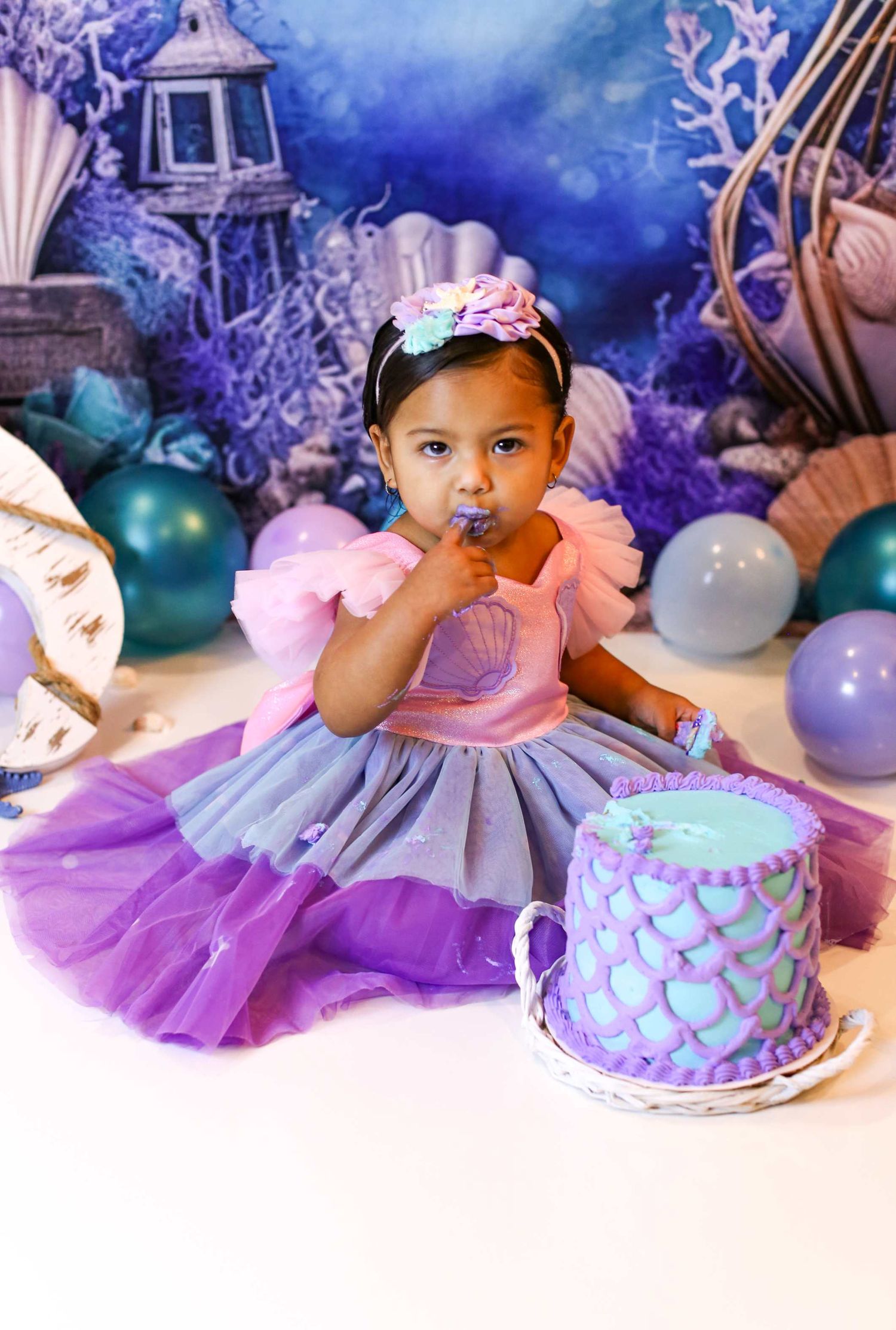 Magical mermaid themed cake smash setup with purple tulle dress and blue mystical backdrop.