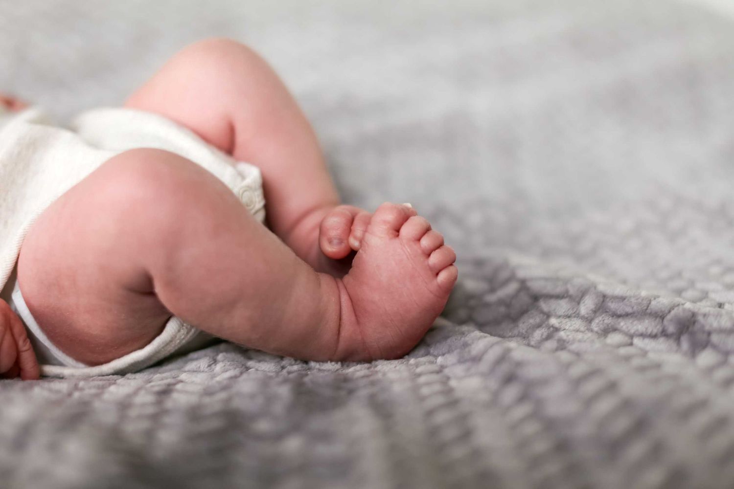 Close-up of tiny newborn baby feet against a soft gray textured background.