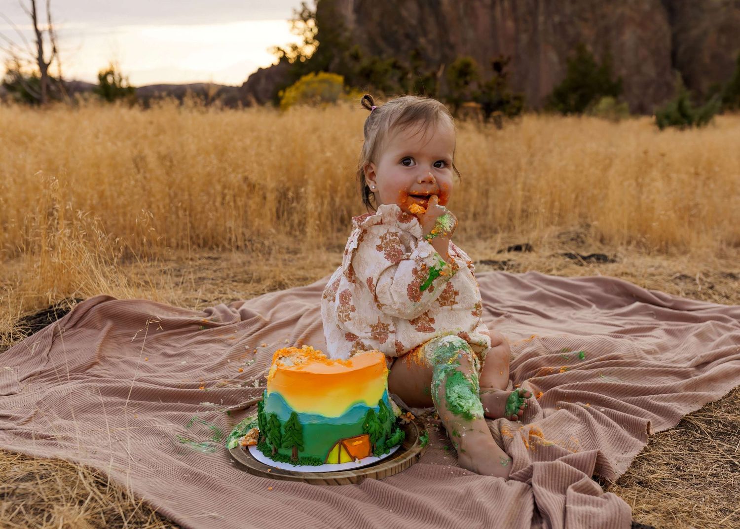 A series of photos showing a cake smash photography session in a golden field with brown blanket.