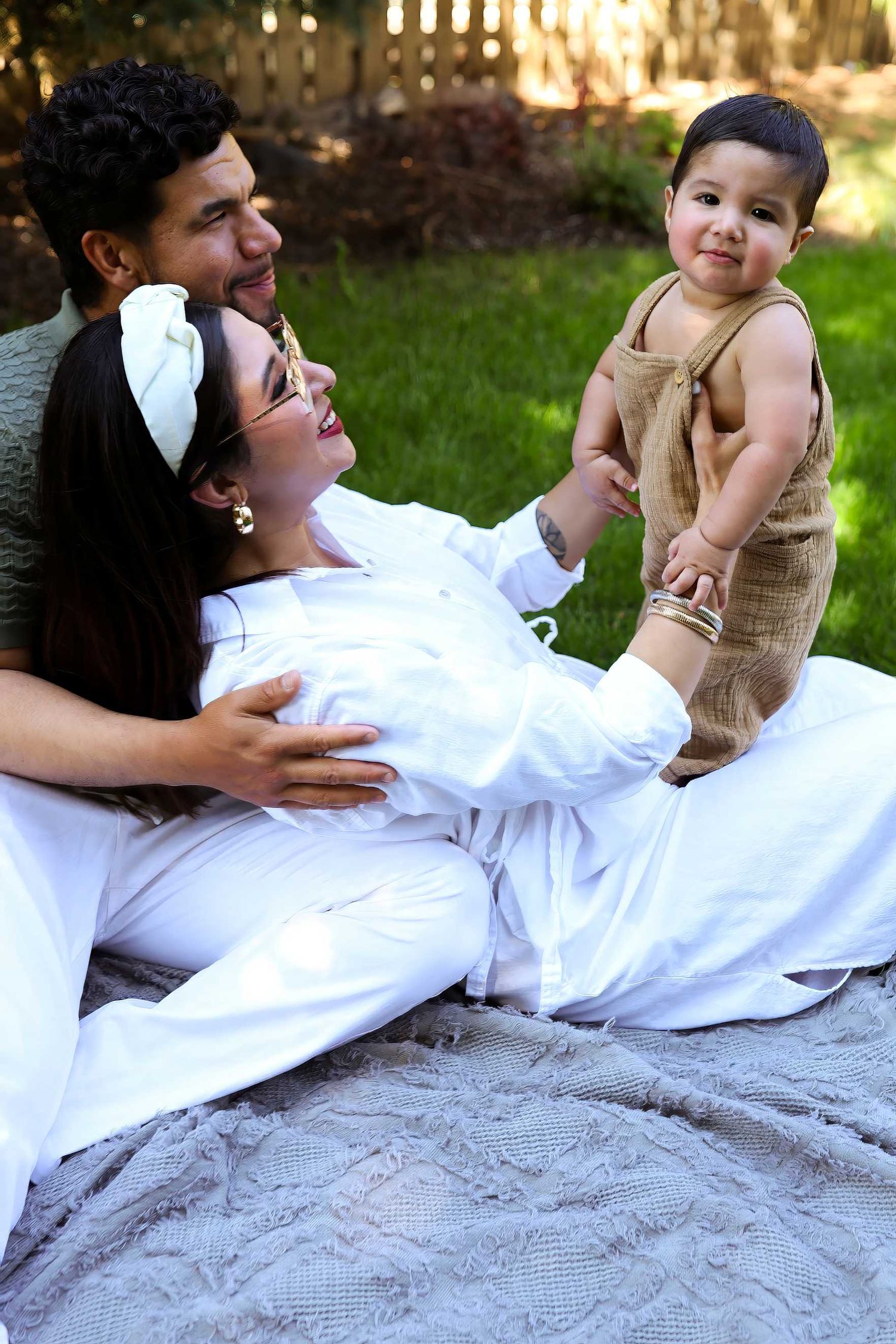 A couple in formal attire shares a candid moment while laying on a blanket outdoors during a photo session.