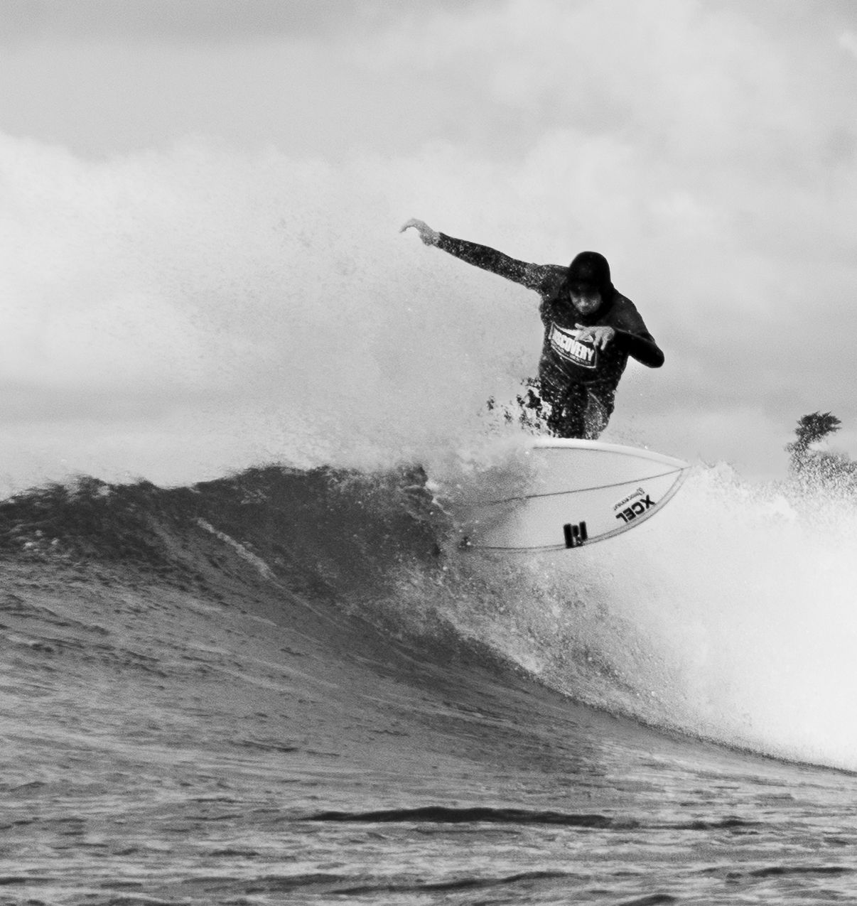 A black and white photo of a surfer completing a top turn during Bantham Board Rider's surf competition, Devon.