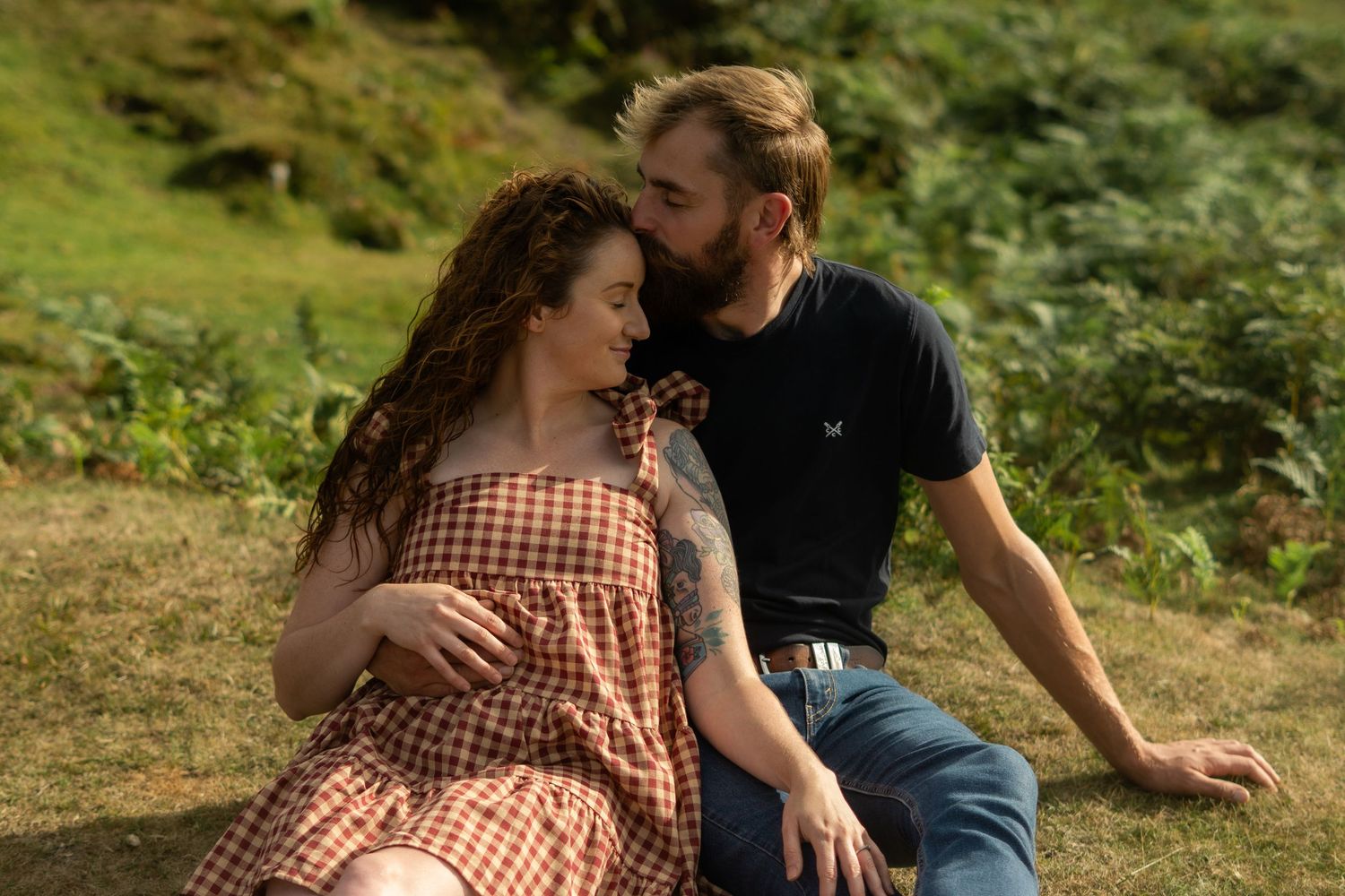 A couple sitting and cuddling on the grass at Dartmoor National Park, Devon, England.
