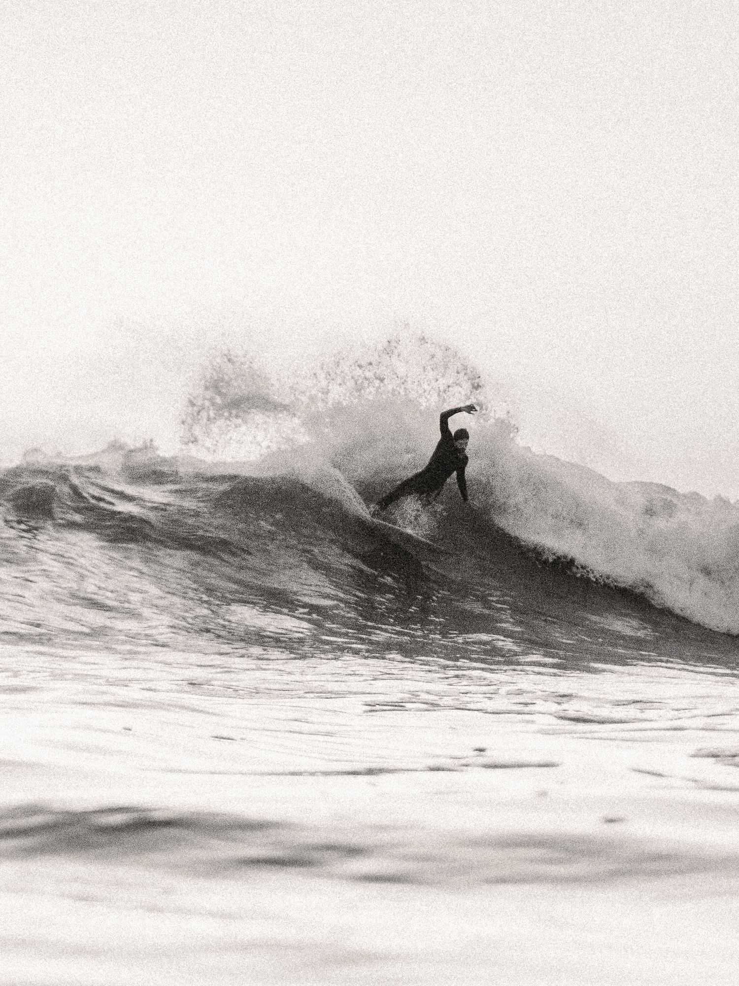 A black and white, in-water photo of a surfer completing a top turn at Bantham Beach, Devon