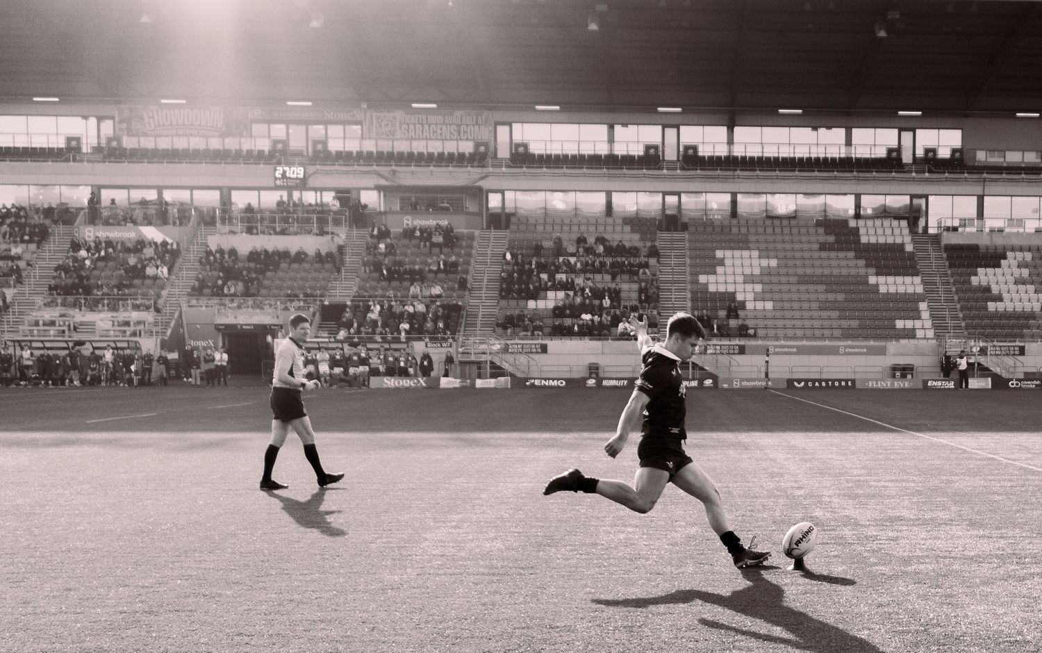 black and white photo of rugby player kicking the ball to convert a try at the StoneX Stadium, North London