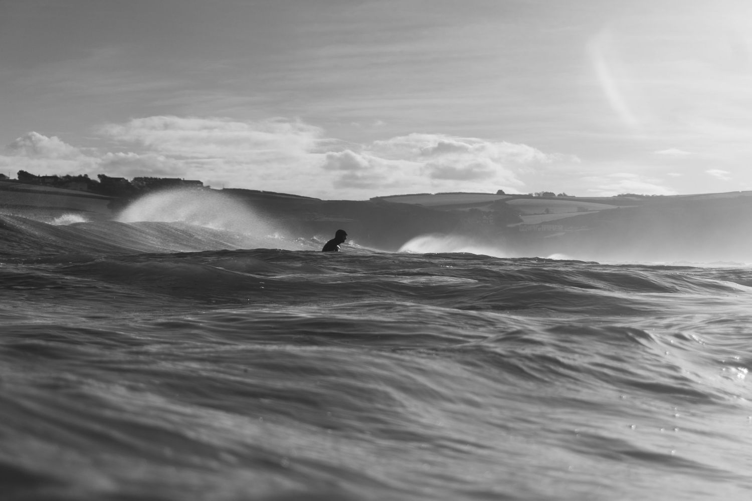 A surfer waiting between waves during a winter swell in Bude, Cornwall