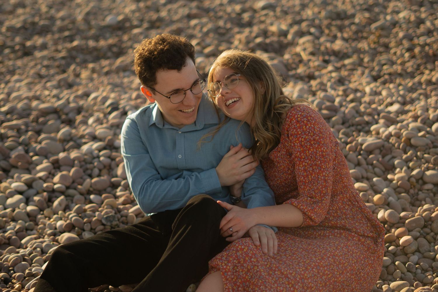 A couple cuddling into one another on the beach during sunset at Budleigh Salterton, Devon