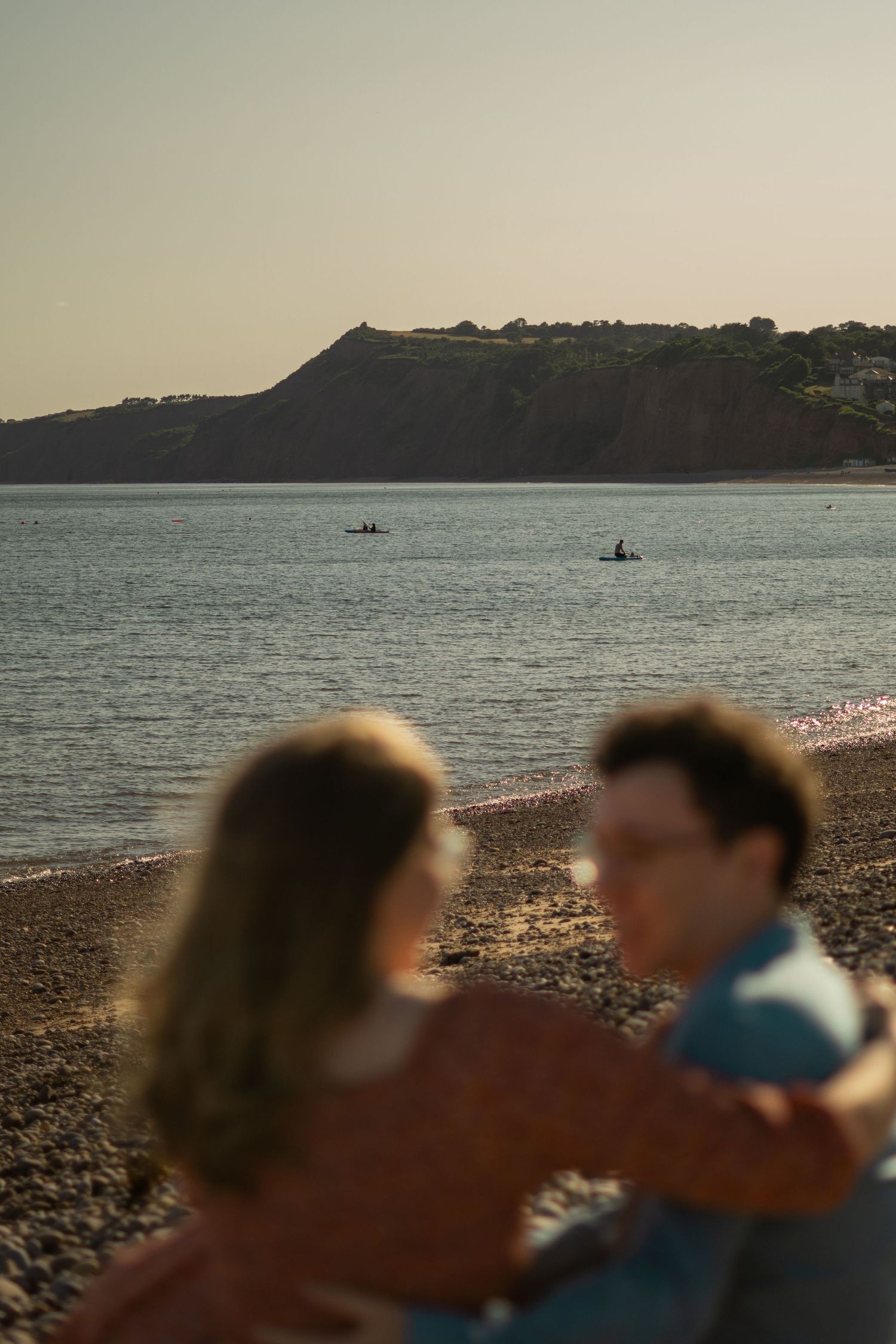 A couple sat together on the beach during sunset at Budleigh Salterton, Devon