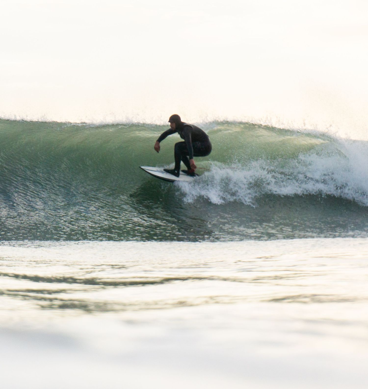 An in-water photo of a surfer riding a wave at Bantham Beach, Devon during sunset.