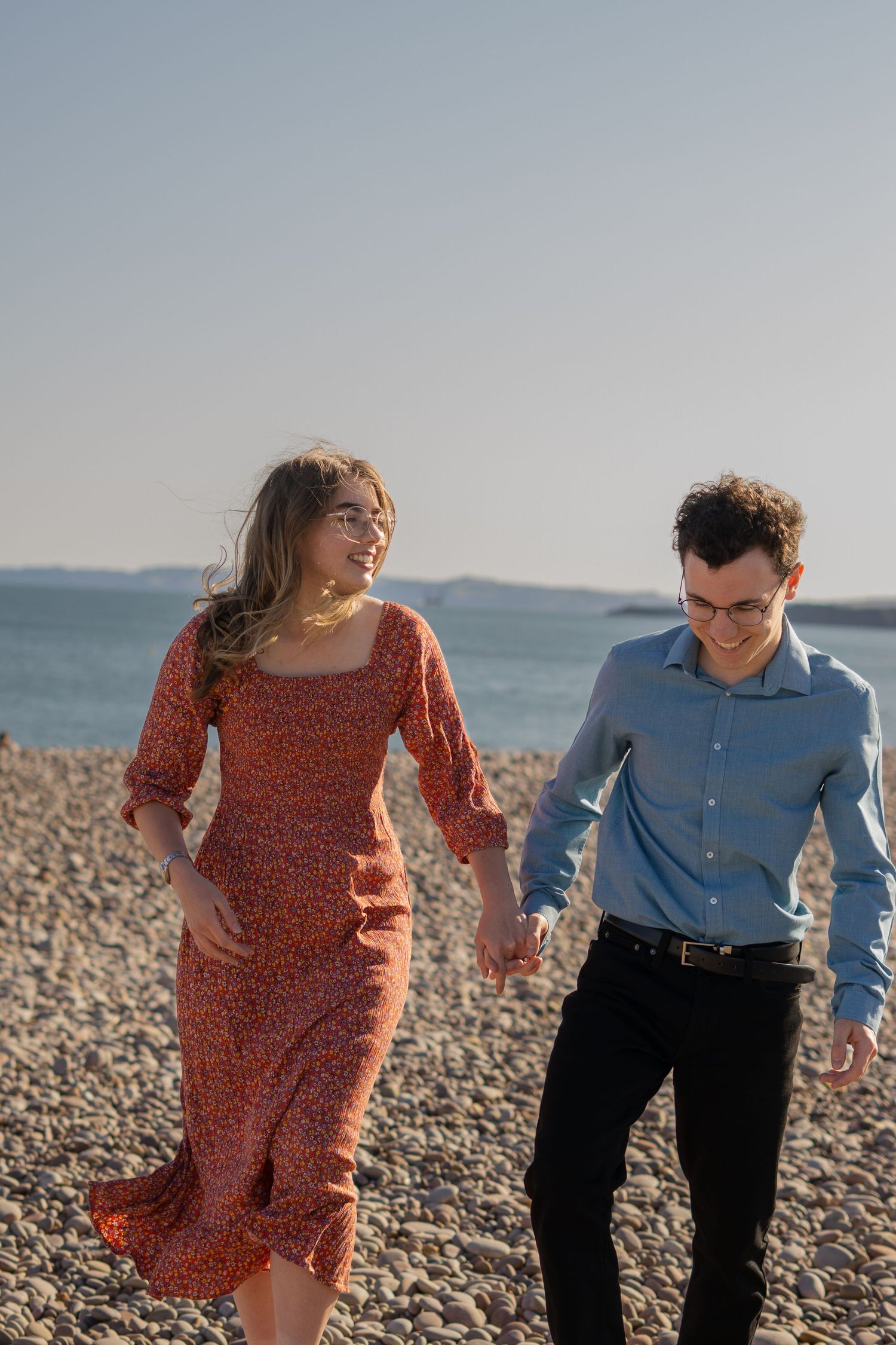 A couple walking and laughing during a walk on Budleigh Salterton beach, Devon.