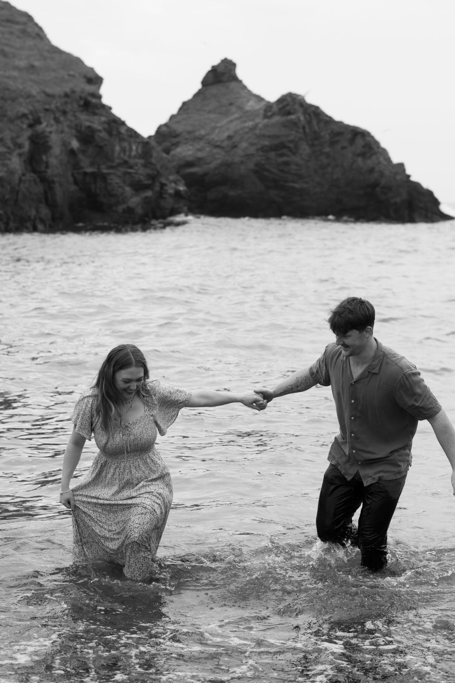 A black and white photo of a couple in the ocean together at Park Head near Porthcothan Bay in Cornwall.