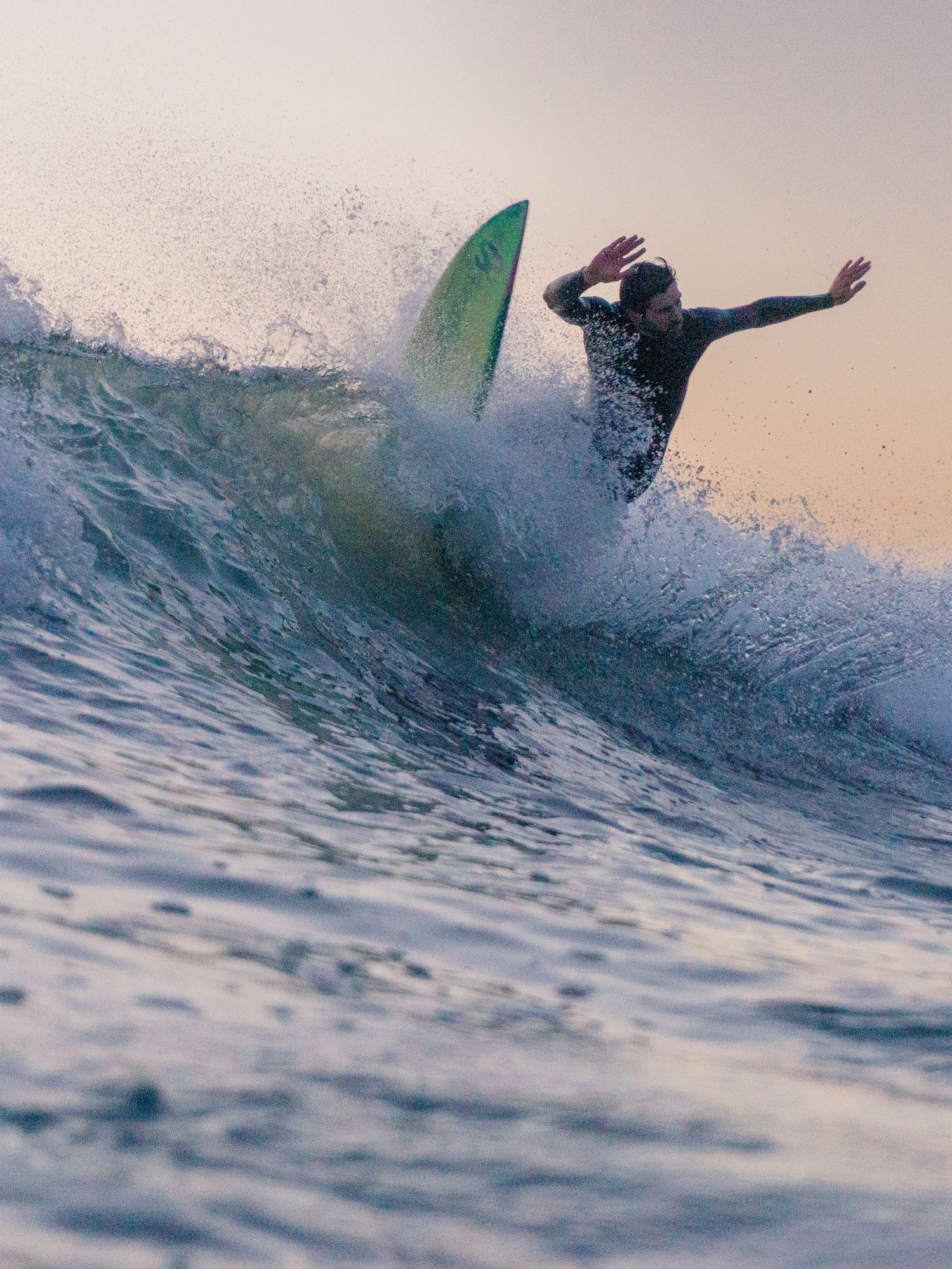 An in-water photo of a surfer hitting the lip at Bantham Beach, Devon during sunset.