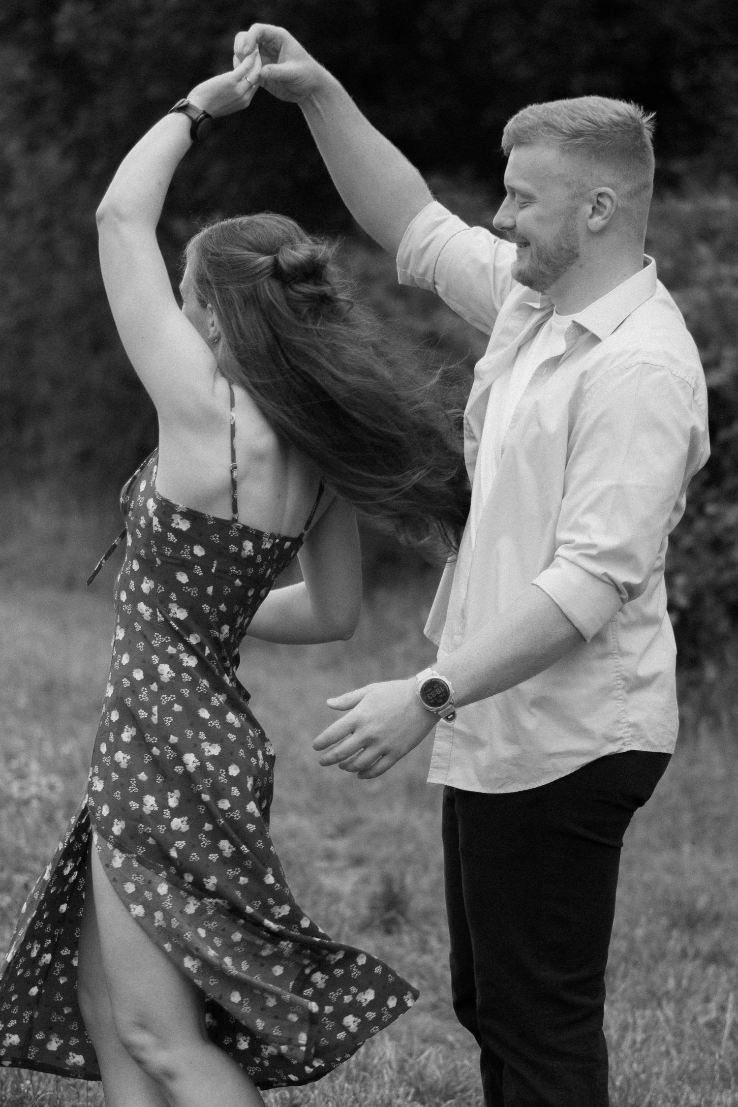 A black and white photo of a man twirling his fiancé during a dog walk in Devon