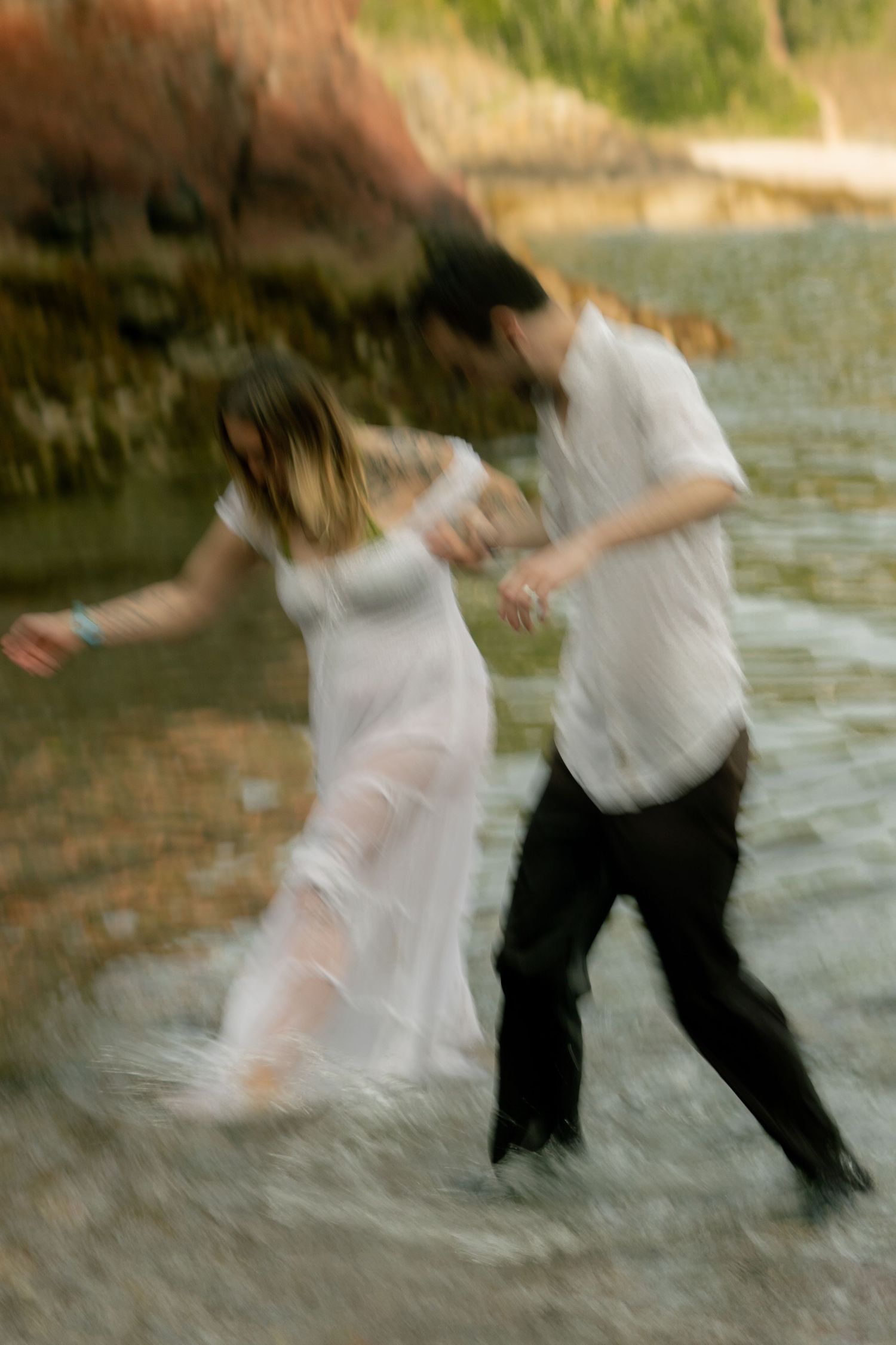 A motion blur photo of fiancés playing in the sea during their engagement photoshoot at Churston Cove, Devon. Captured with slow shutter.