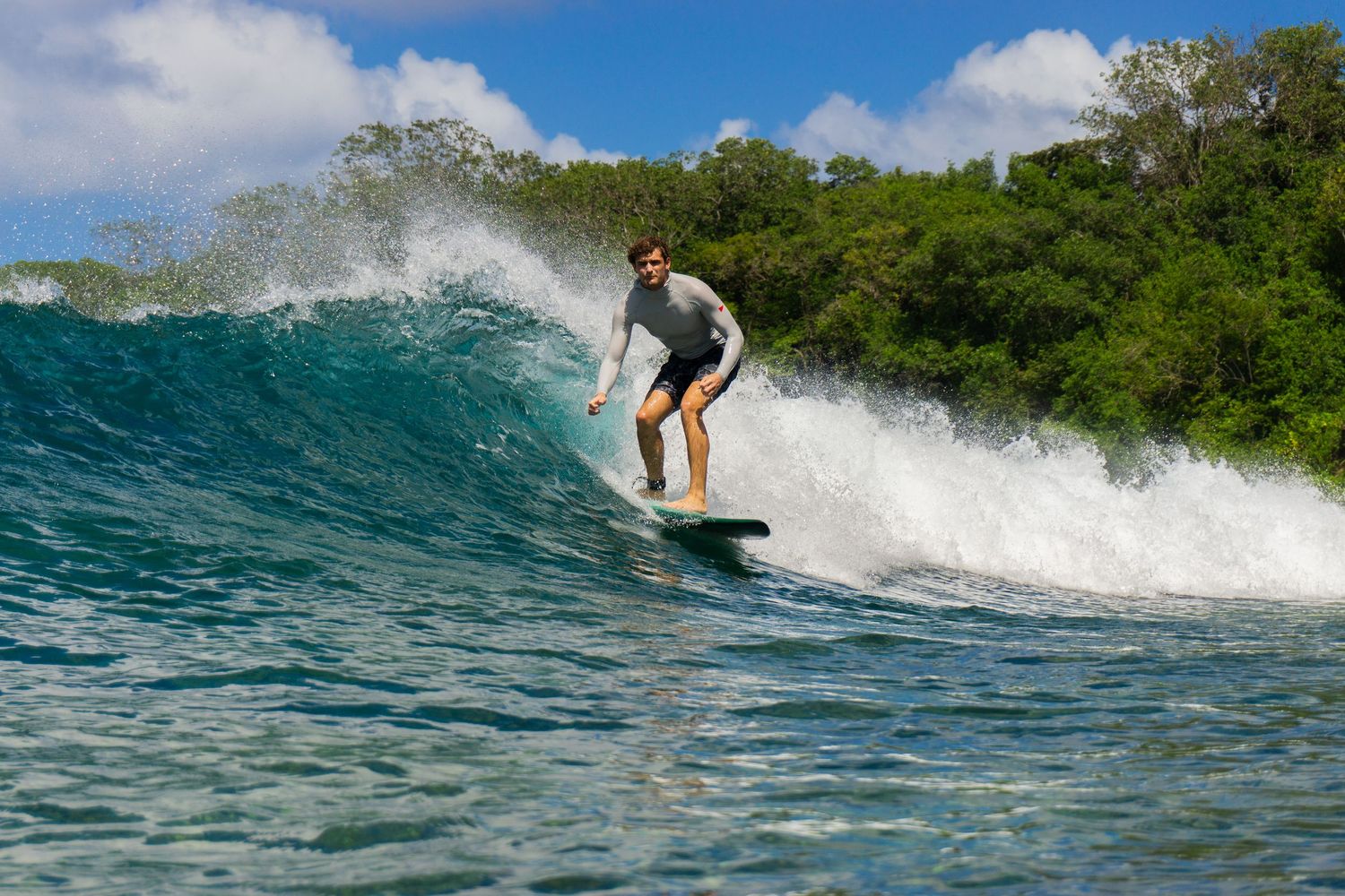 A surfer catching a tube wave in the turquoise sea at Mt Irvine beach, Tobago