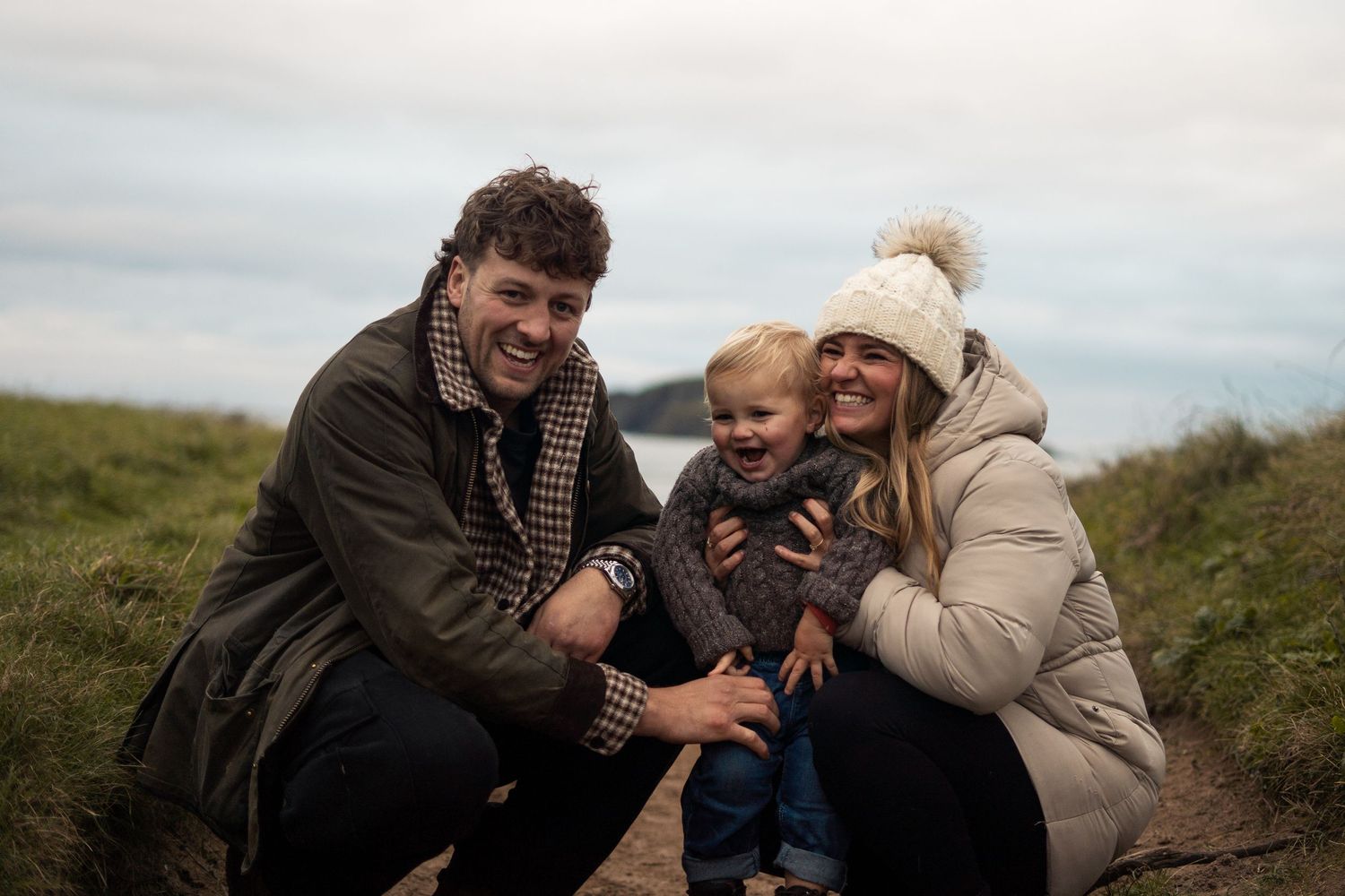 A mum, dad, and son laughing during a family photoshoot on Bantham Beach, South Devon.