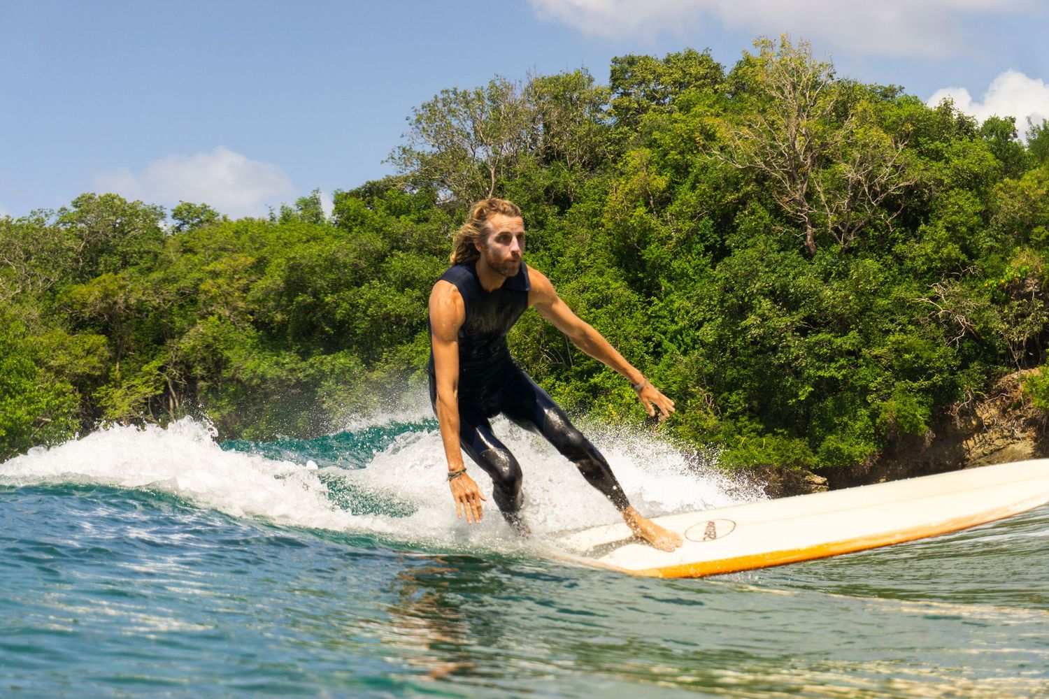 A surfer riding a longboard on Mt Irvine beach, Tobago