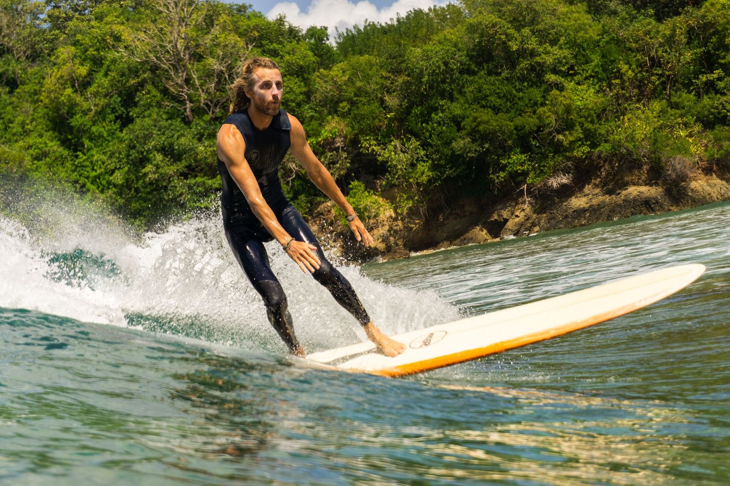A longboard surfer gliding on a wave at Mt Irvine beach, Tobago