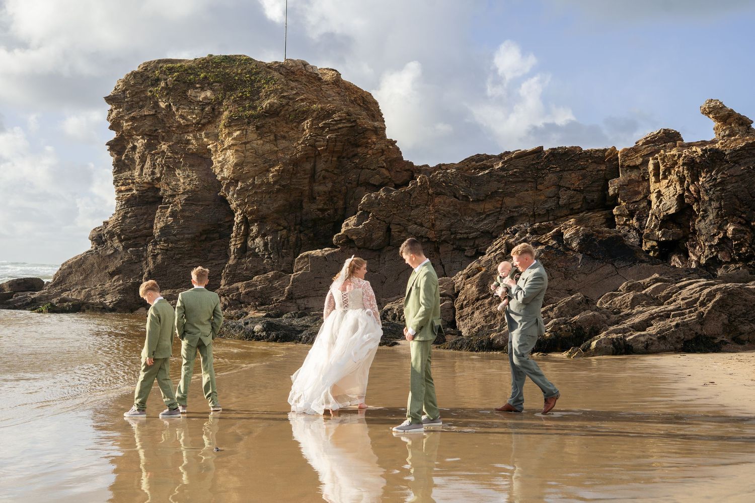 A family walking towards the ocean during an intimate wedding photoshoot on Perranporth Beach, Cornwall.