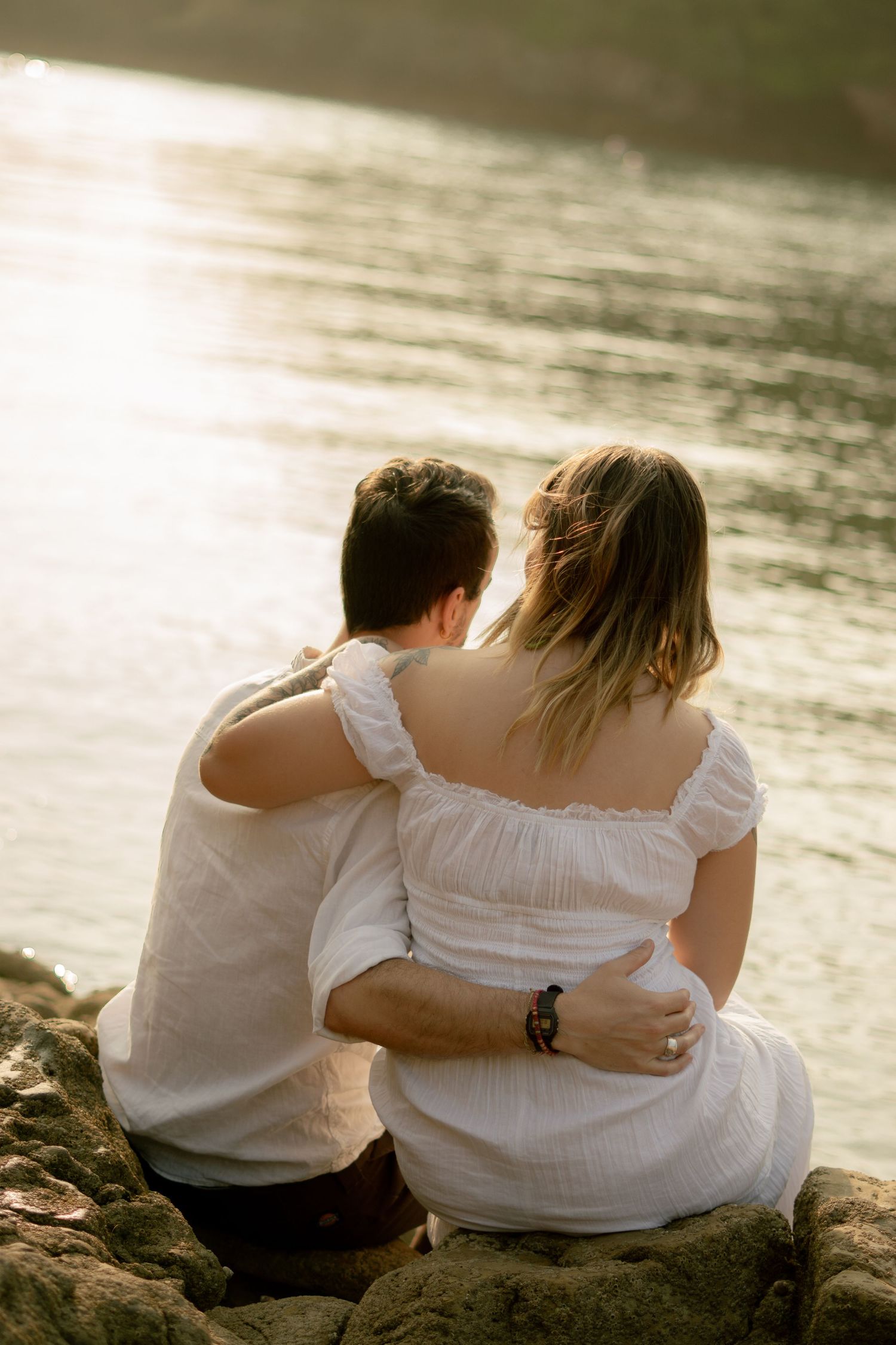 An engaged couple sitting and looking out to sea at Churston Cove, Devon.