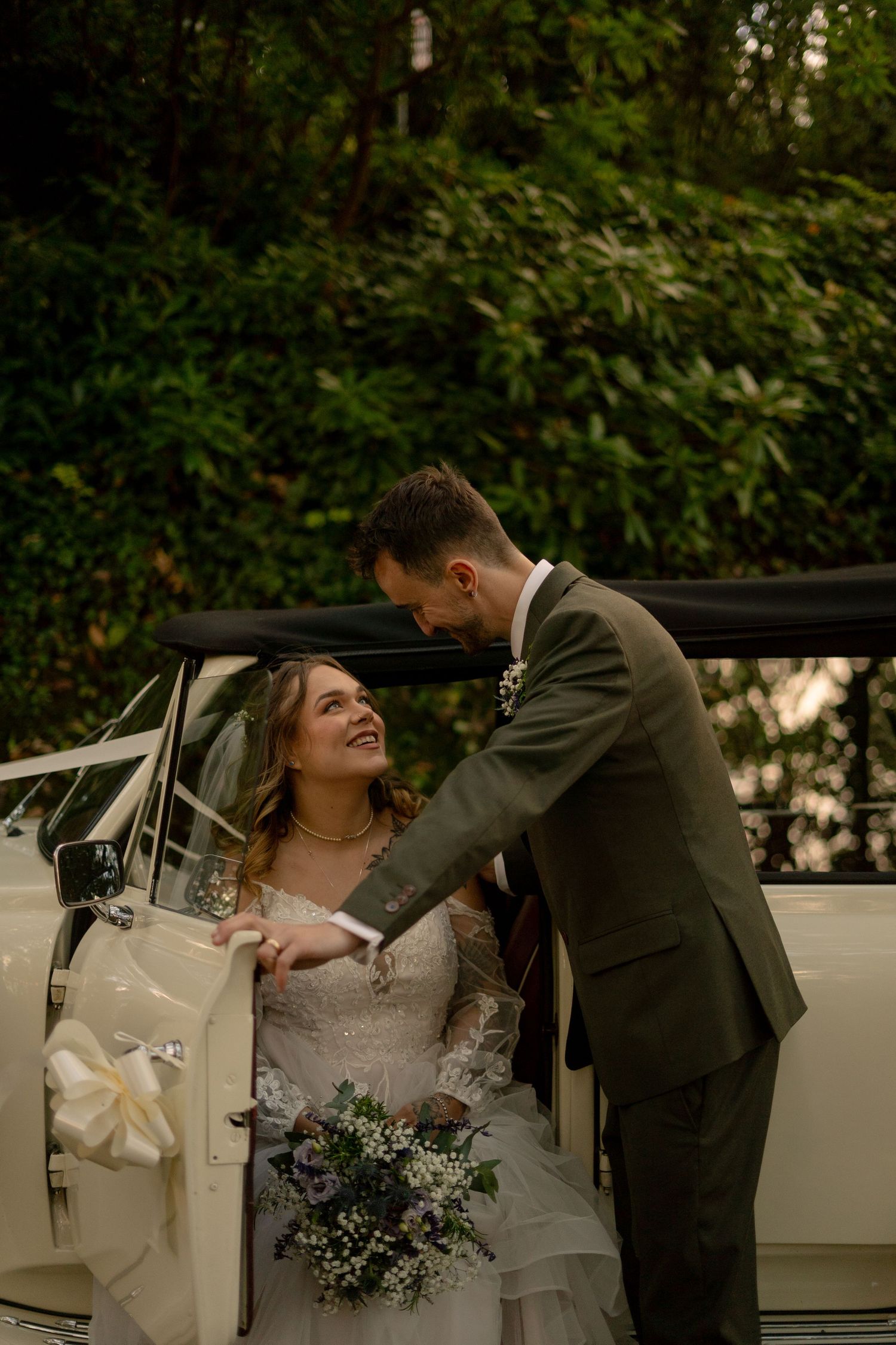 A groom helping his bride out of their vintage car to explore Watermouth Castle after their wedding ceremony in Berrynarber, North Devon.
