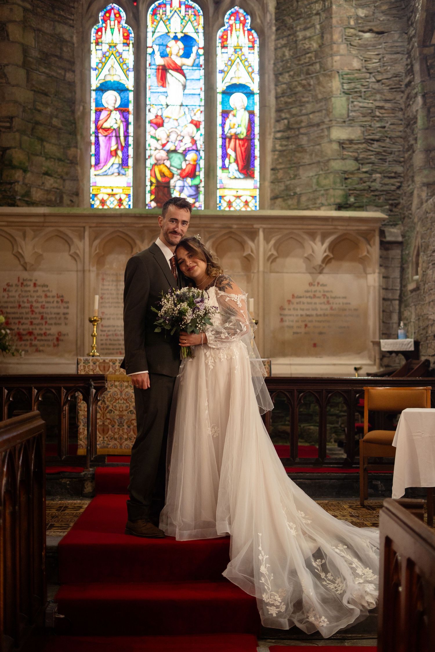The bride leans on her groom at the alter in St. Peter's Church, Berrynarber, North Devon.