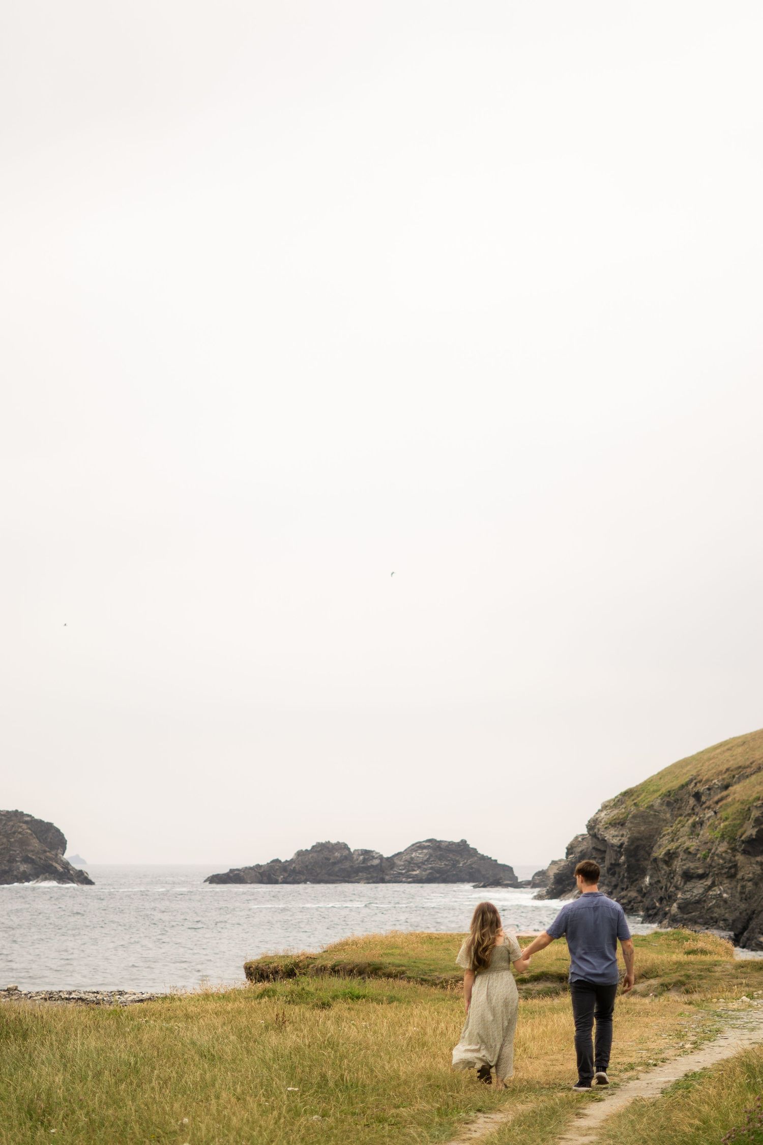A couple walking towards the beach at Park Head near Porthcothan Bay in Cornwall.