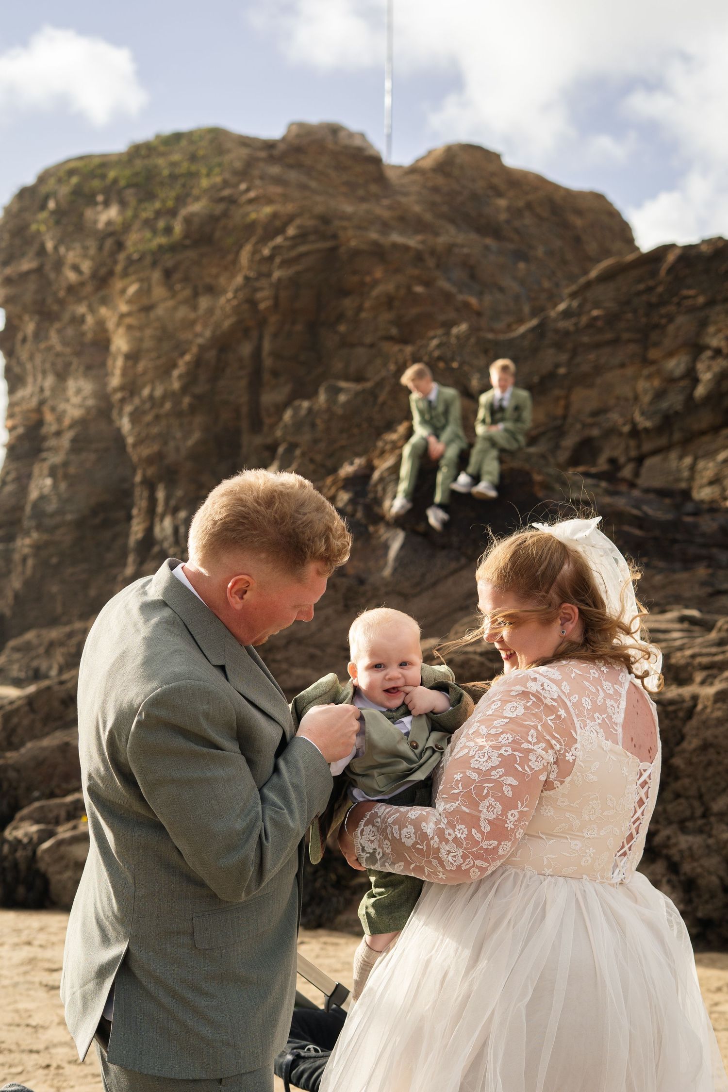 A family photo on Perranporth beach, Cornwall after an intimate registry office ceremony in Truro. The mother and father hold the baby.