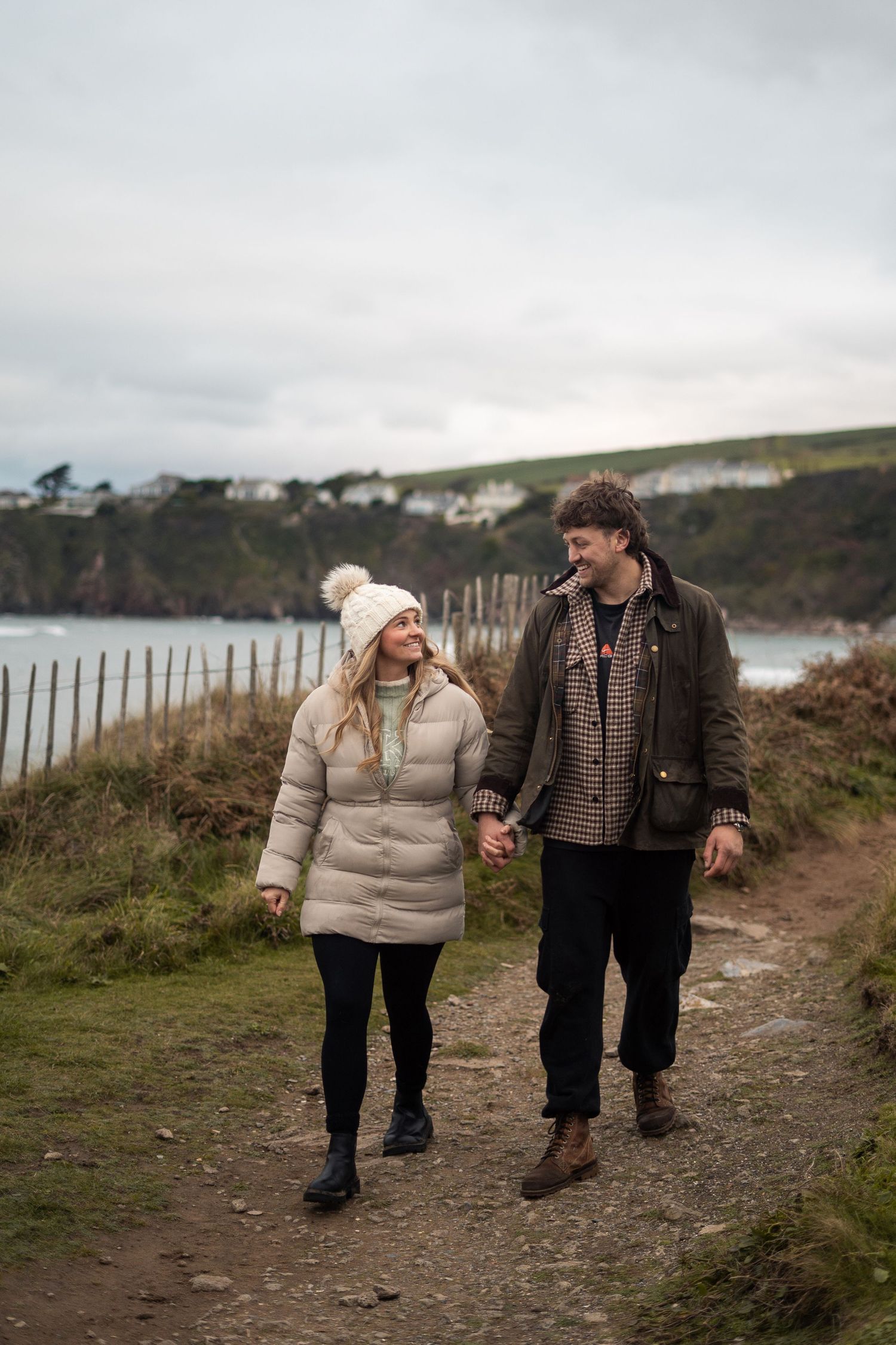 Fiancés walking hand-in-hand during an engagement photo session on Bantham Beach, South Devon.
