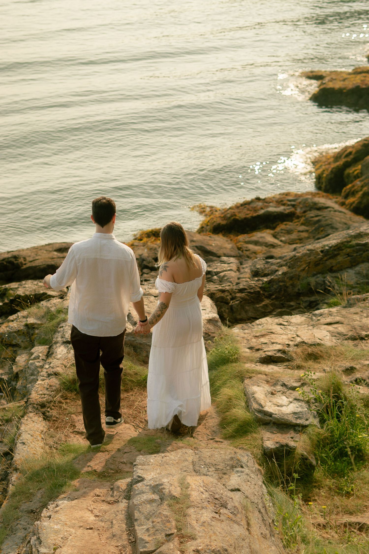 A couple walking hand-in-hand along the cliffs at Churston Cove, Devon