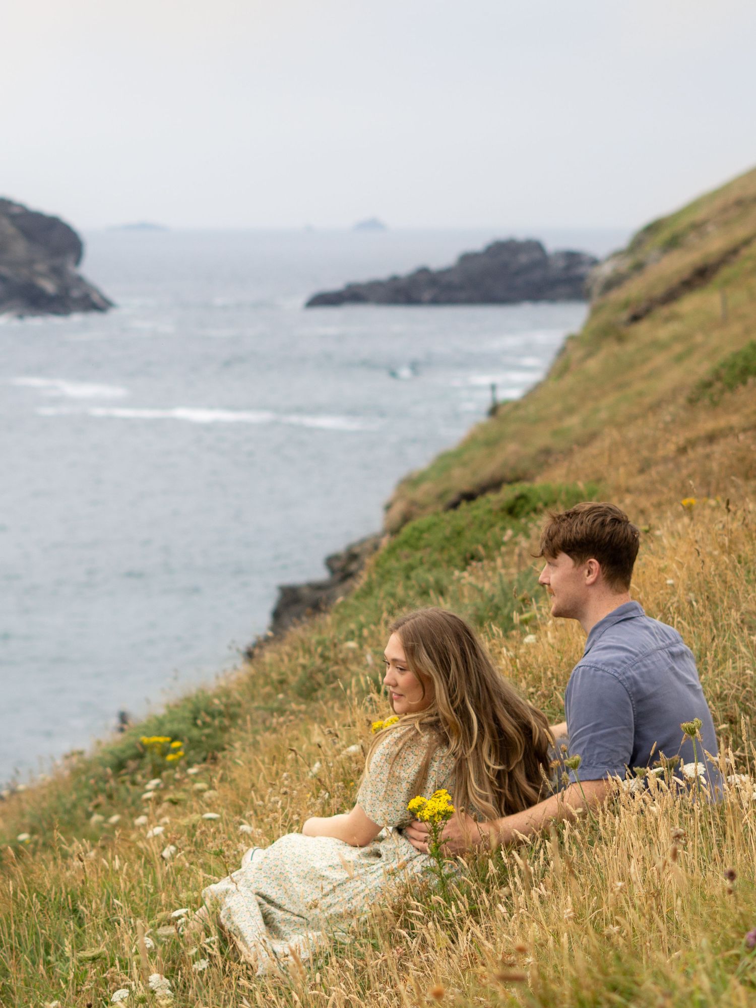 A couple cuddling on the clifftop at Park Head near Porthcothan Bay in Cornwall.