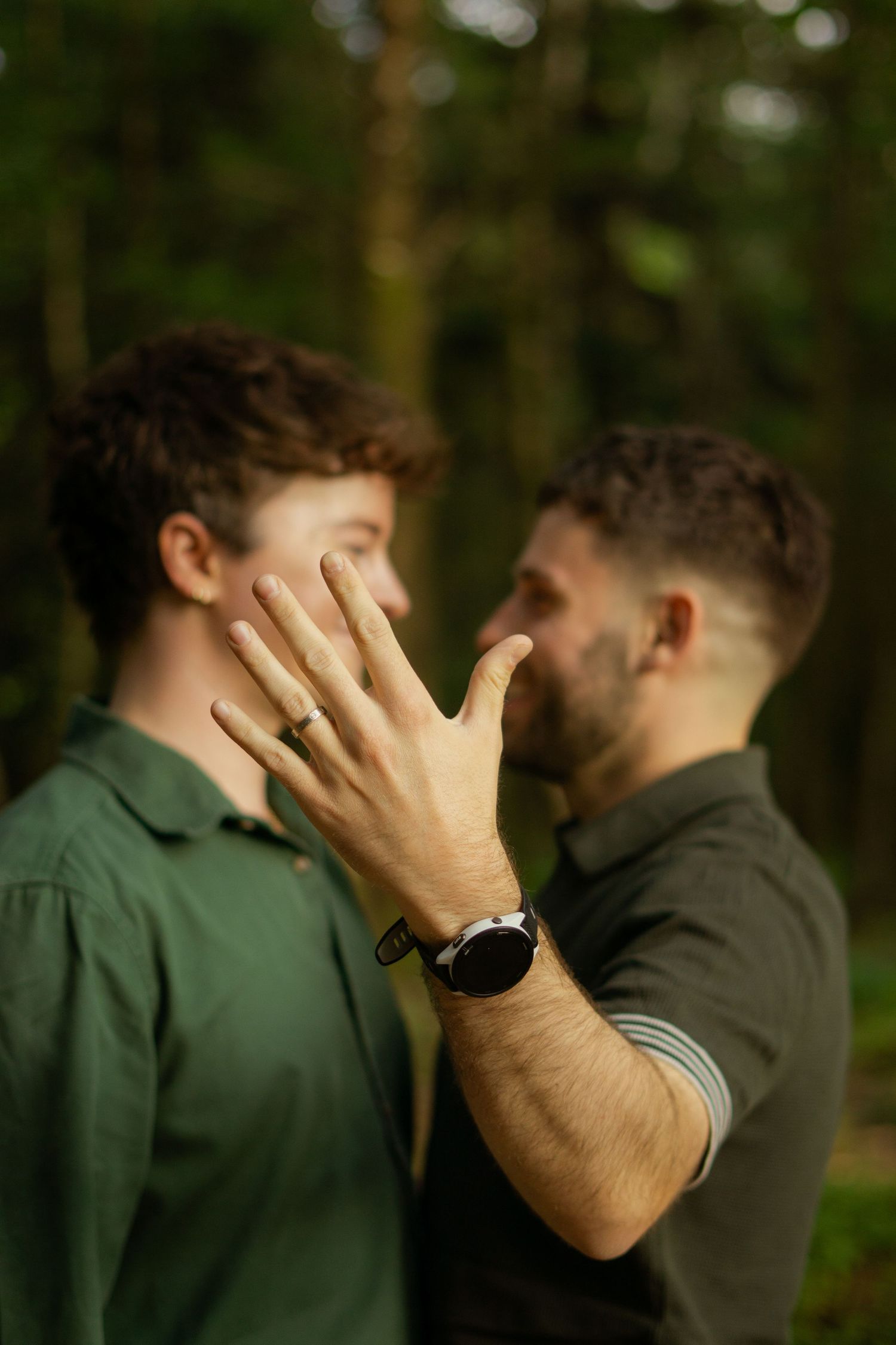 An LGBT engagement photo, with the ring being held up in front of both of their faces.