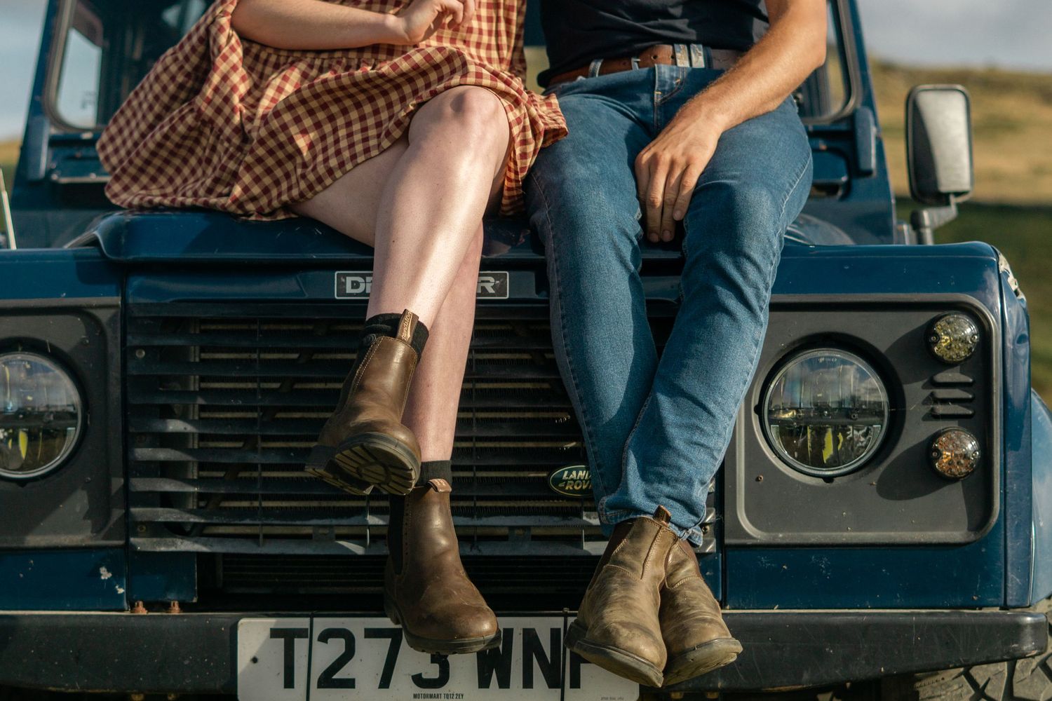 A couple sitting on the bonnet of their land rover at Dartmoor National Park, Devon.