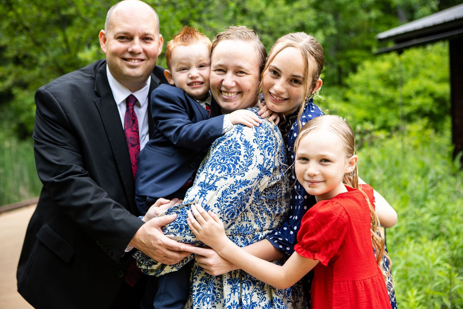 Joyful family moment captured outdoors in lush green setting.