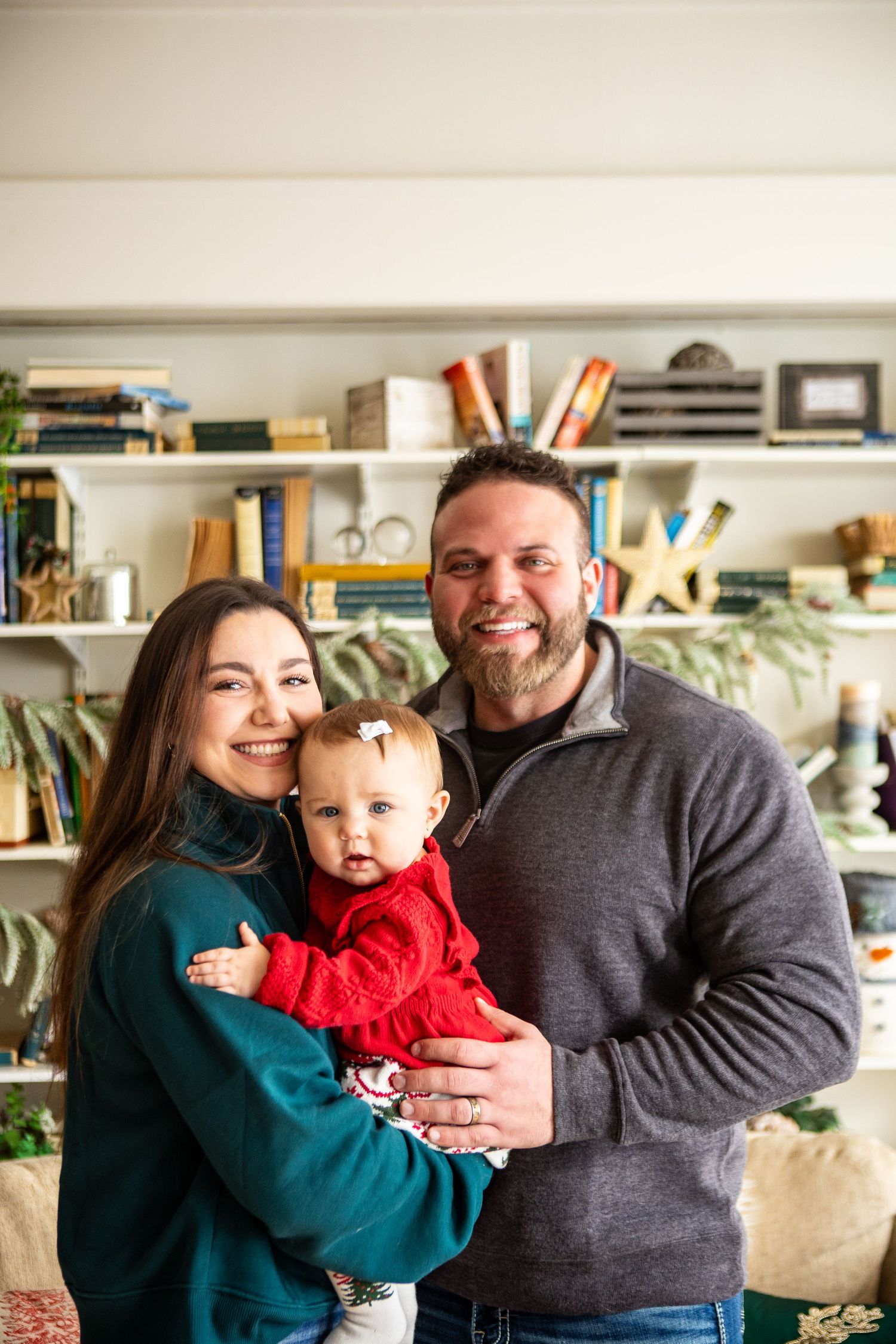 Family wearing blue and grey sweaters share joyful moments together in a cozy living room with bookshelves.