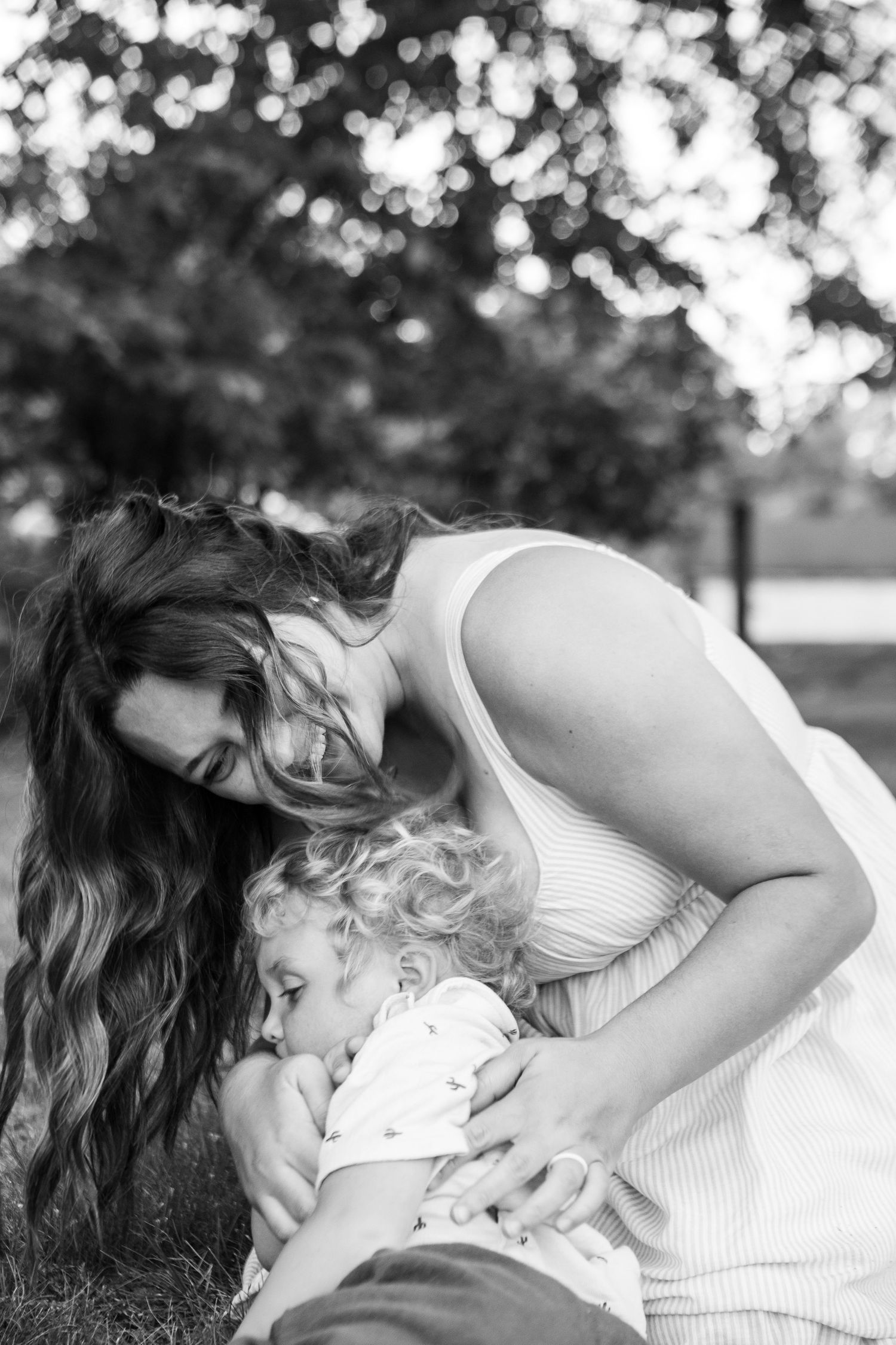 Tender black and white portrait showing intimate family moment outdoors.