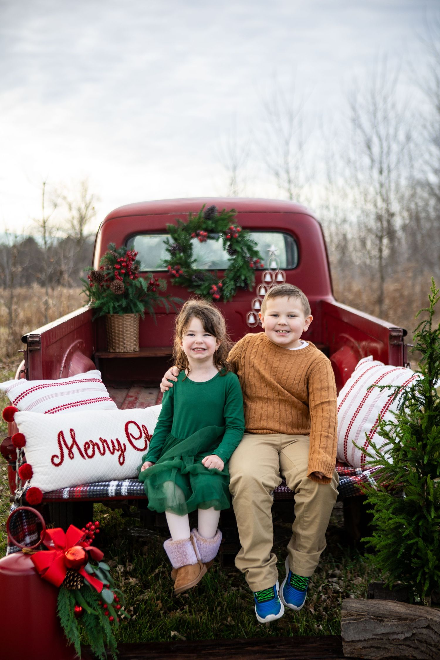 Vintage red pickup truck decorated with Christmas greenery and festive holiday decor in a winter setting.