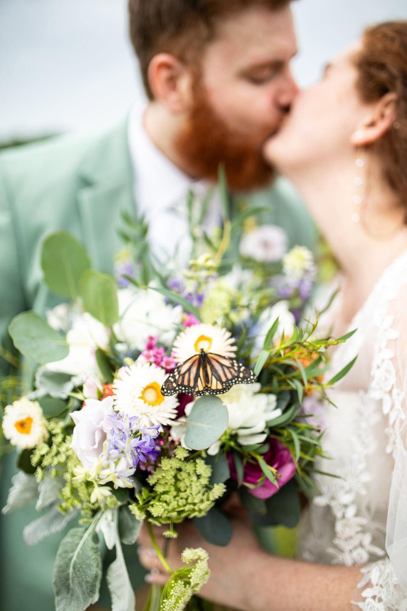 Romantic wedding photo series featuring colorful wildflower bouquet with monarch butterfly.