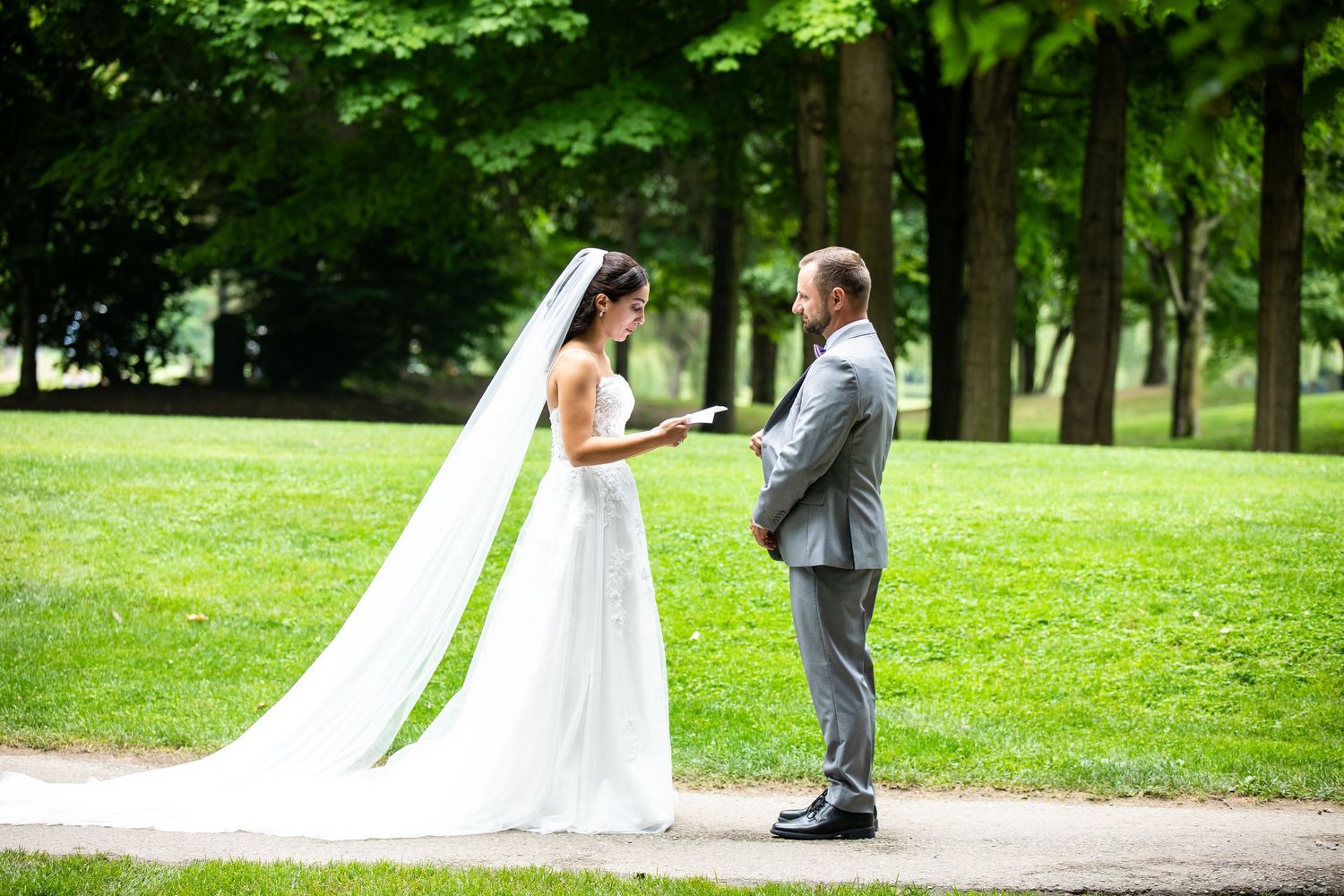 Romantic wedding first look moment captured in a lush green park setting.