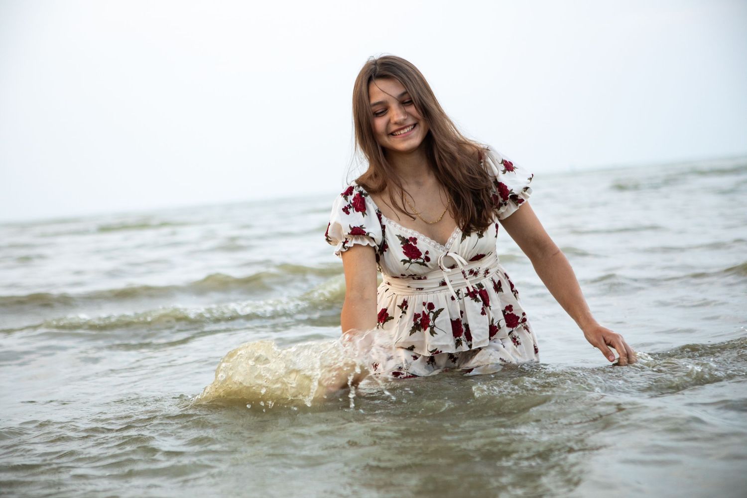 A sequence of splashing water photos at the beach shows a person in a floral dress playing in the ocean waves.