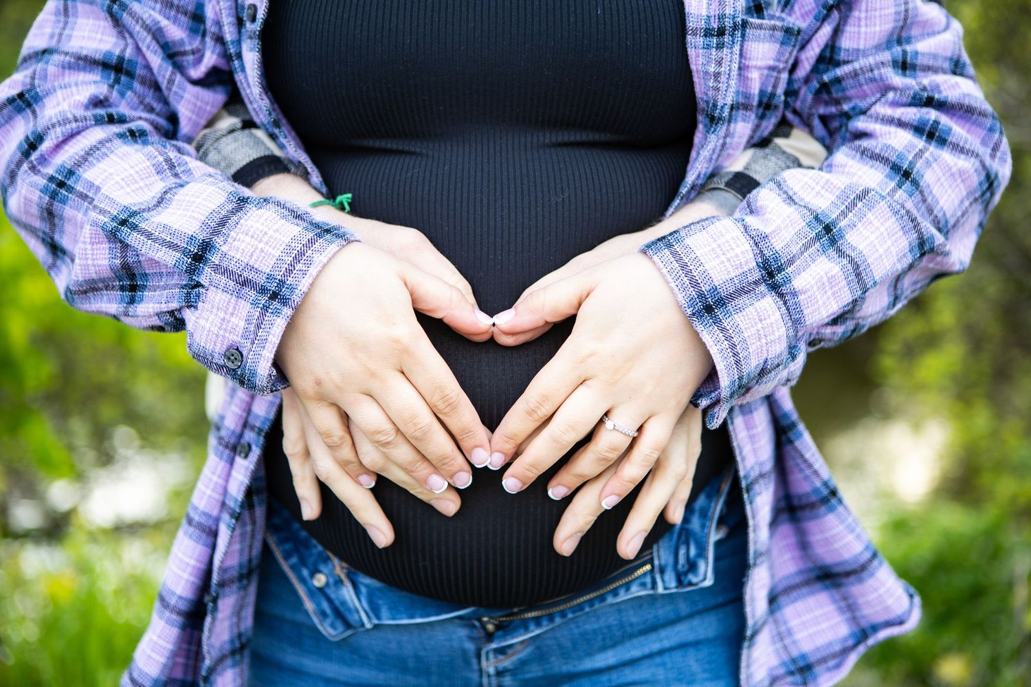 Maternity photo series showing hands framing pregnant belly in plaid shirt.