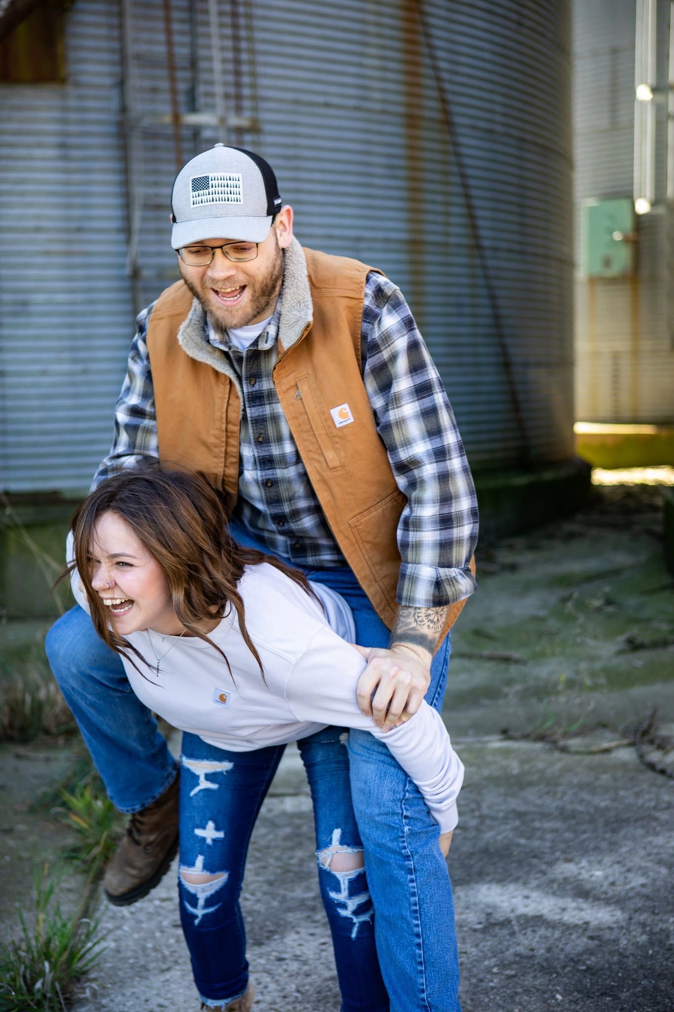 Playful outdoor photoshoot near a metal building with plaid shirt and jeans.